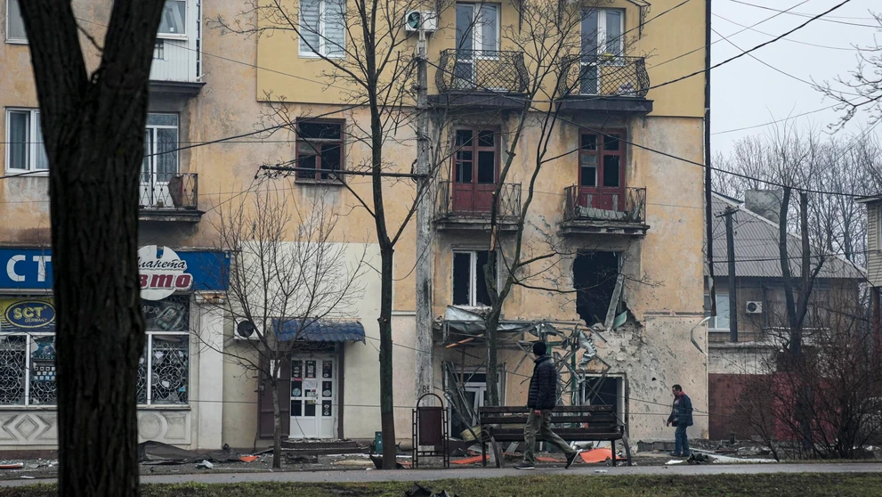 Muž prechádza okolo obytného domu zasiahnutého ostreľovaním v Mariupole na Ukrajine.