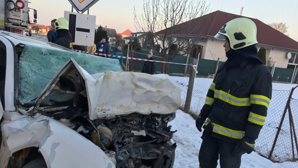 Hasič stojí pri osobnom aute, ktorého predok zdemolovala čelná zrážka s autobusom v Trebaticiach.