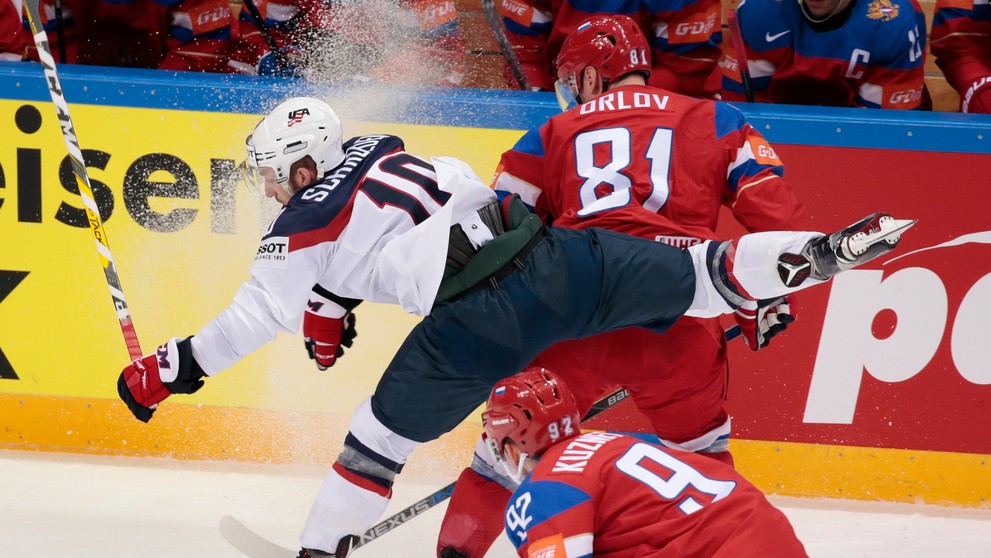 Dmitrij Orlov (hore) tvrdo zastavuje amerického hráča Jordana Schroedera (vľavo) v zápase na MS v Rusku