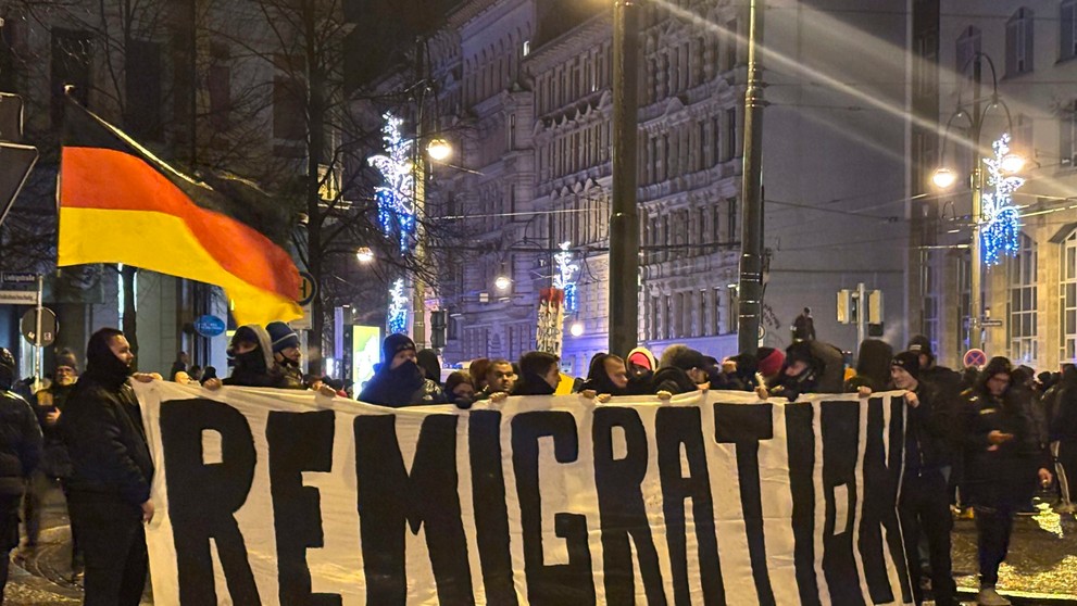 Prívrženci krajnej pravice s transparentom počas bohoslužby v Magdeburgu za obete nešťastia.