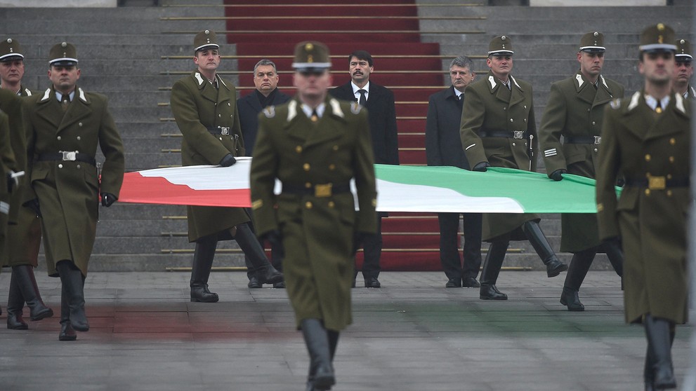 Maďarský premiér Viktor Orbán, maďarský prezident János Áder a predseda parlamentu László Kövér kráčajú pred vojakmi, ktorí nesú