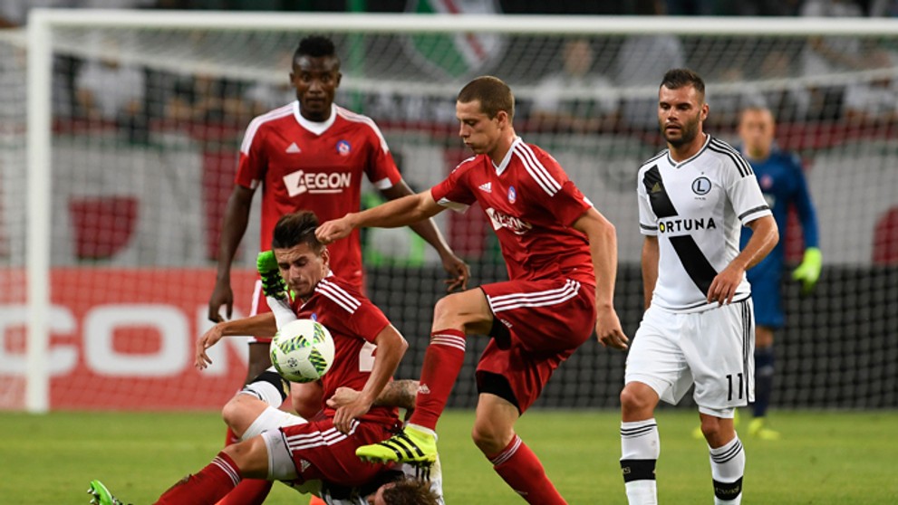 Trenčania Denis Jančo (dole), Christopher Udeh (vľavo vzadu), James Lawrence (druhý sprava) a hráči Varšavy Nemanja Nikolič (vpr