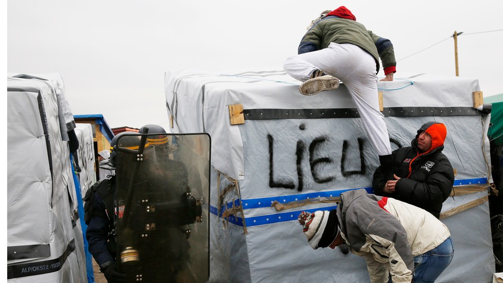 Migranti v tábore pri Calais protestujú na strechách búd.