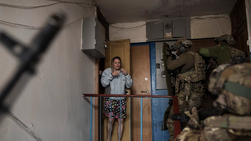 Vystrašená žena sa pozerá na príslušníkov ukrajinskej tajnej služby SBU, ktori prišli zadržať muža podozrivého z kolaborácie s Ruskom.