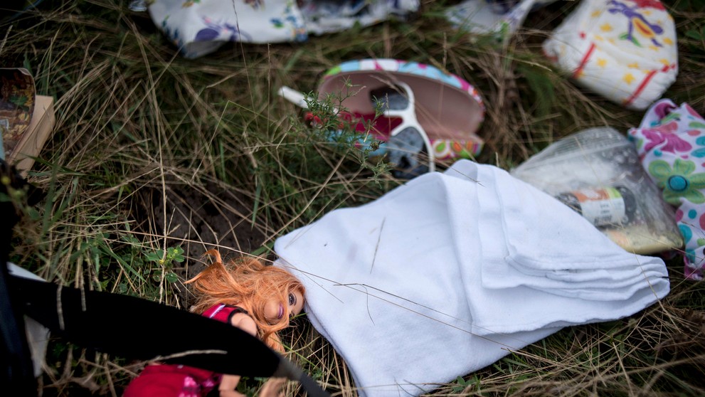 Detská bábika a ďalšie osobné veci ležia na mieste havárie malajzijského lietadka neďaleko obce Hrabovo na východe Ukrajiny.