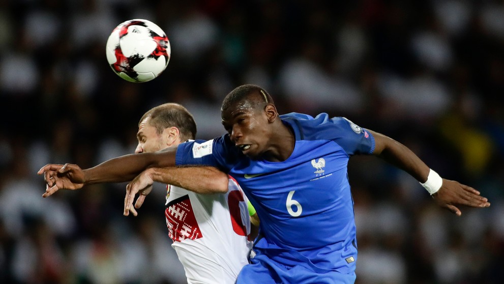 Megahviezda Francúzska Paul Pogba (v modrom) hlavičkuje pred bieloruským Ivanom Majevskim v kvalifikácii MS 2018.
