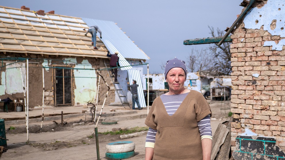 Natália v pozadí s poškodeným domom