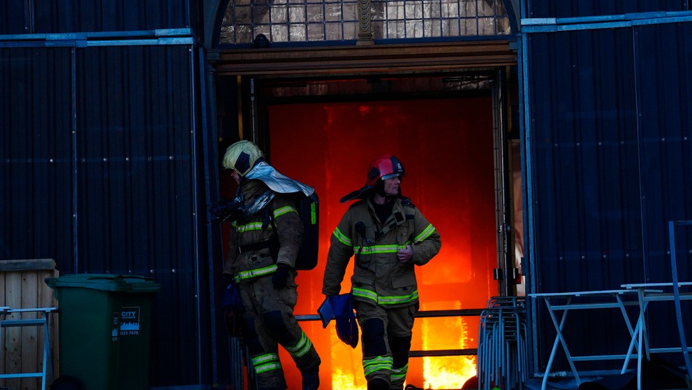 Hasiči pred vchodom historickej budovy.