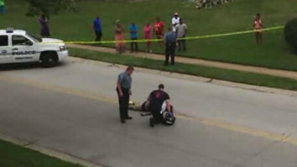 Na videosnímke z 9. augusta 2014 vyšetrovatelia kontrolujú telo Michaela Browna v americkom Fergusone.