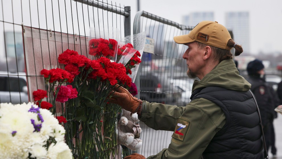 Muž kladie kvety na plot neďaleko radnice Crocus na západnom okraji Moskvy.