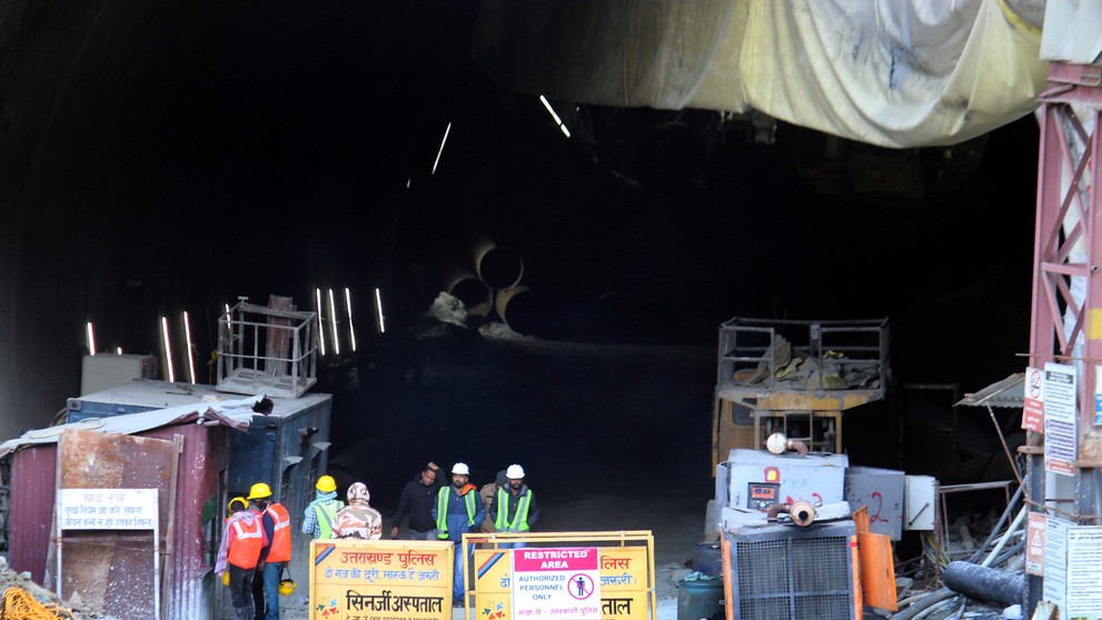 Indickí záchranári stoja pri  zrútenom cestnom tuneli, v ktorom uviazlo asi 40 robotníkov