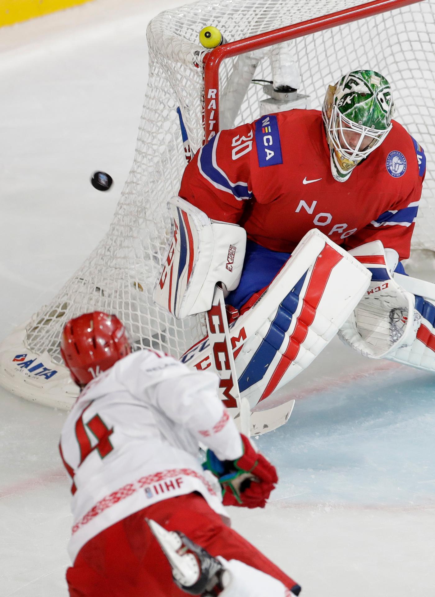 Bielorus Jevgenij Lisovec (vľavo) strieľa na brankára Nórov Larsa Haugena.