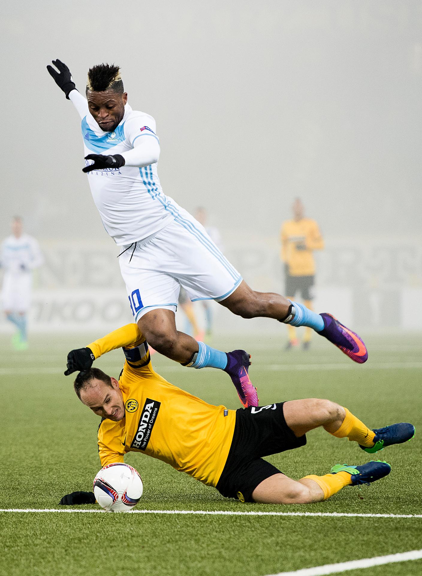 Steve von Bergen (dole) z YB Bern sa snaží zastaviť Juniora Kabanangu z Astany v dueli EL. 