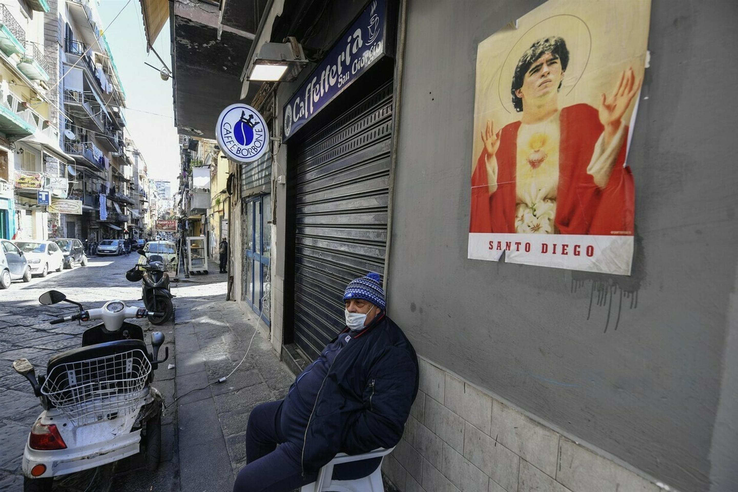 Dôchodca s rúškom sedí pred domom na ulici v Neapole.