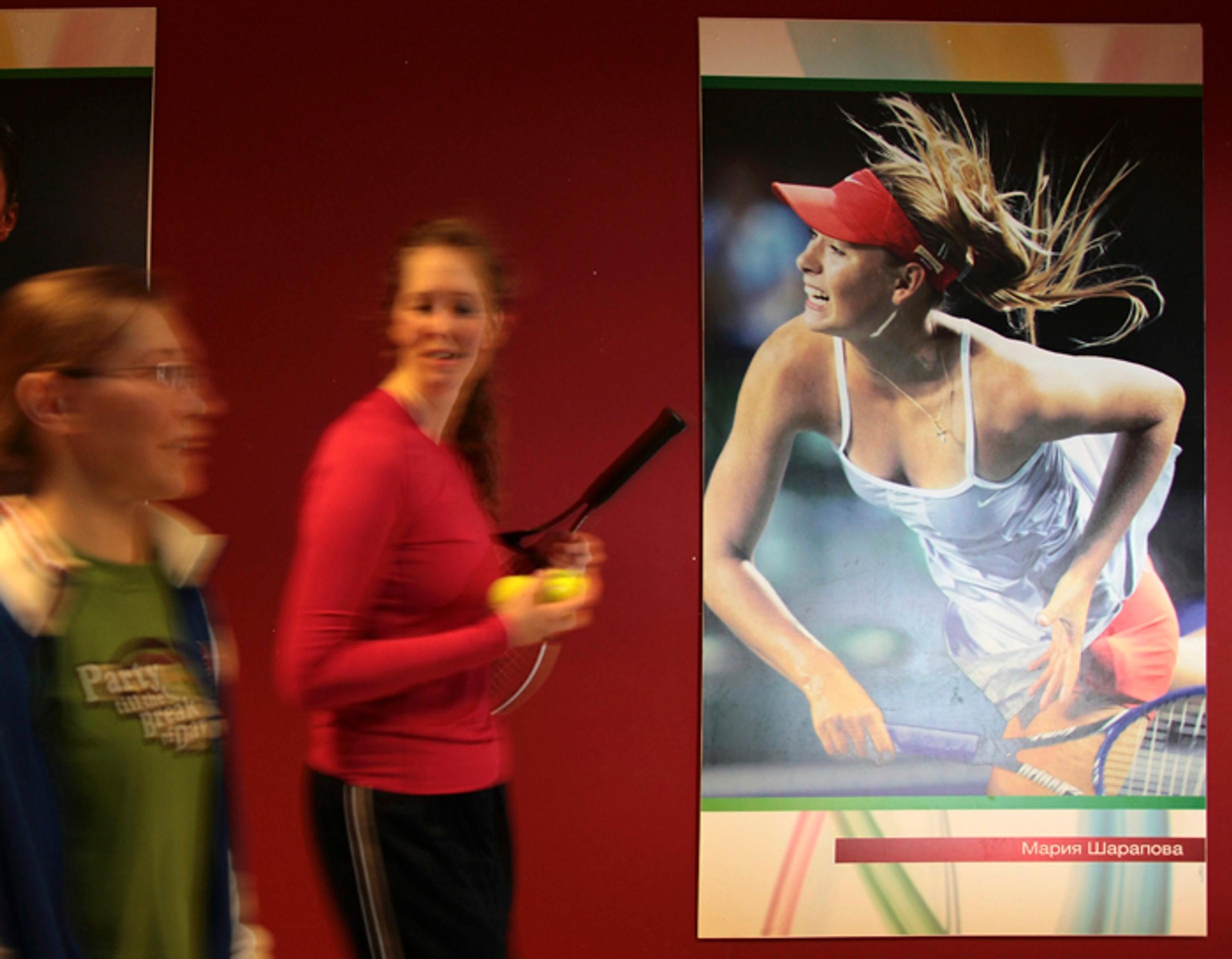 Študentky tenisovej akadémie kráčajú okolo plagátu s podobizňou ruskej tenistky Marie Šarapovovej v Kazani.