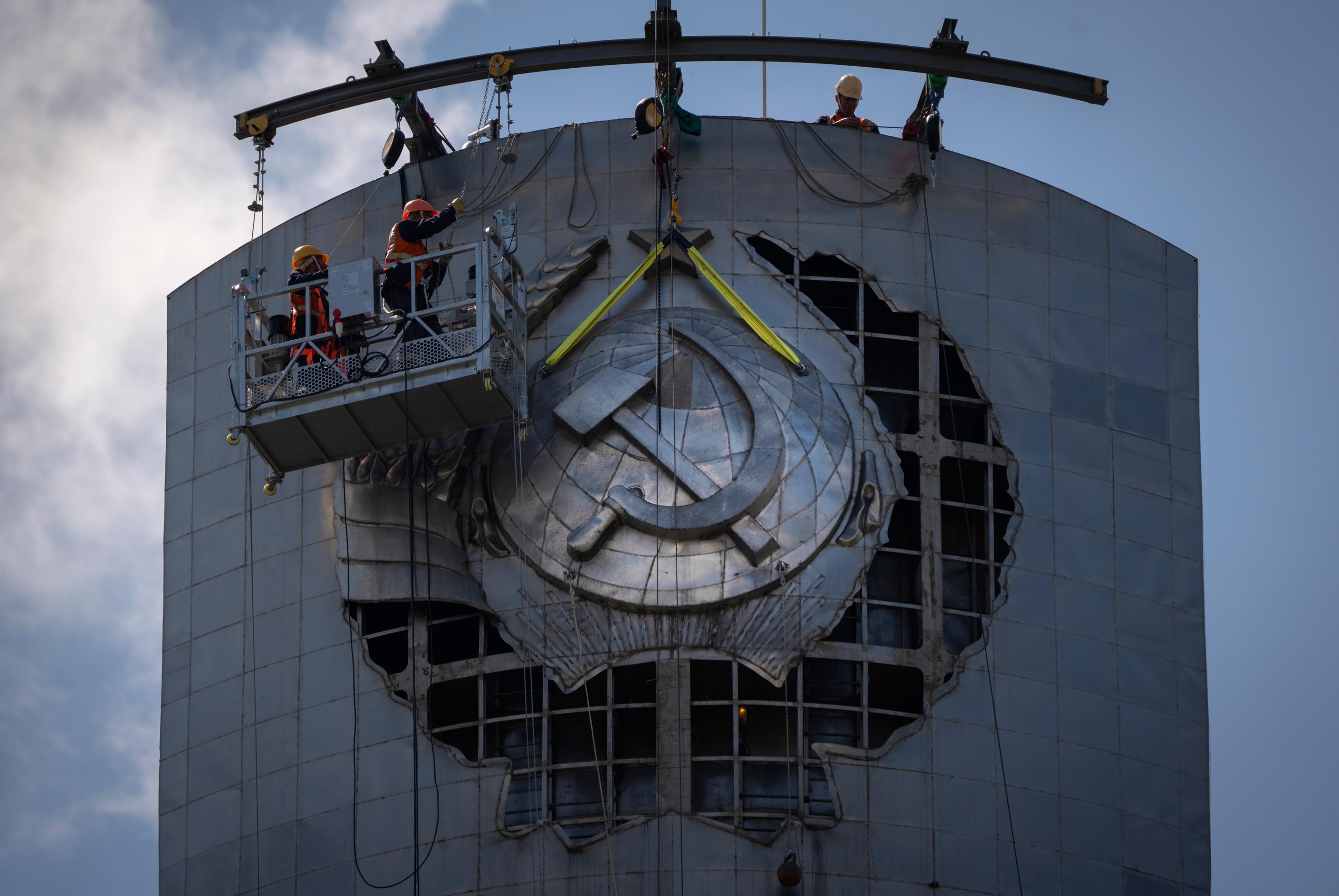 Robotníci odstraňujú štátny znak bývalého Sovietskeho zväzu z obrovskej sochy Matka Vlasť v Kyjeve.