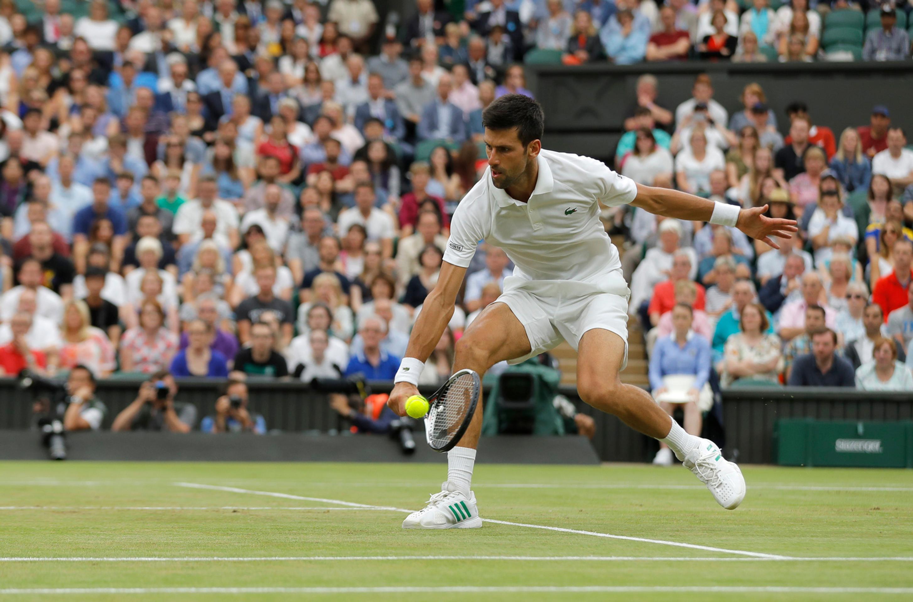 Novak Djokovič odvracia úder Adriana Mannarina v osemfinále Wimbledonu.