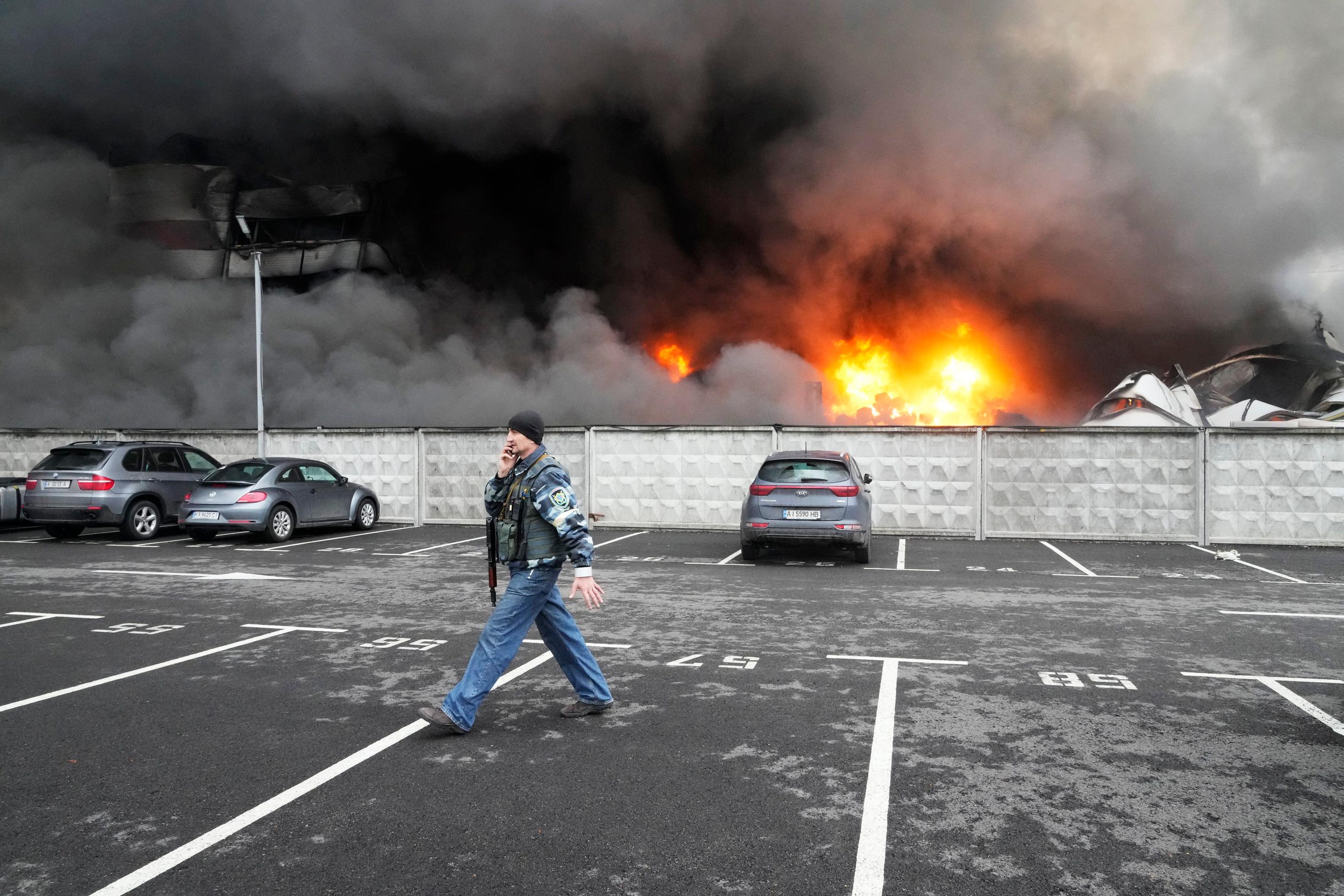 Ukrajinský vojak prechádza okolo poškodeného logistického centra po ostreľovaní v Kyjeve.