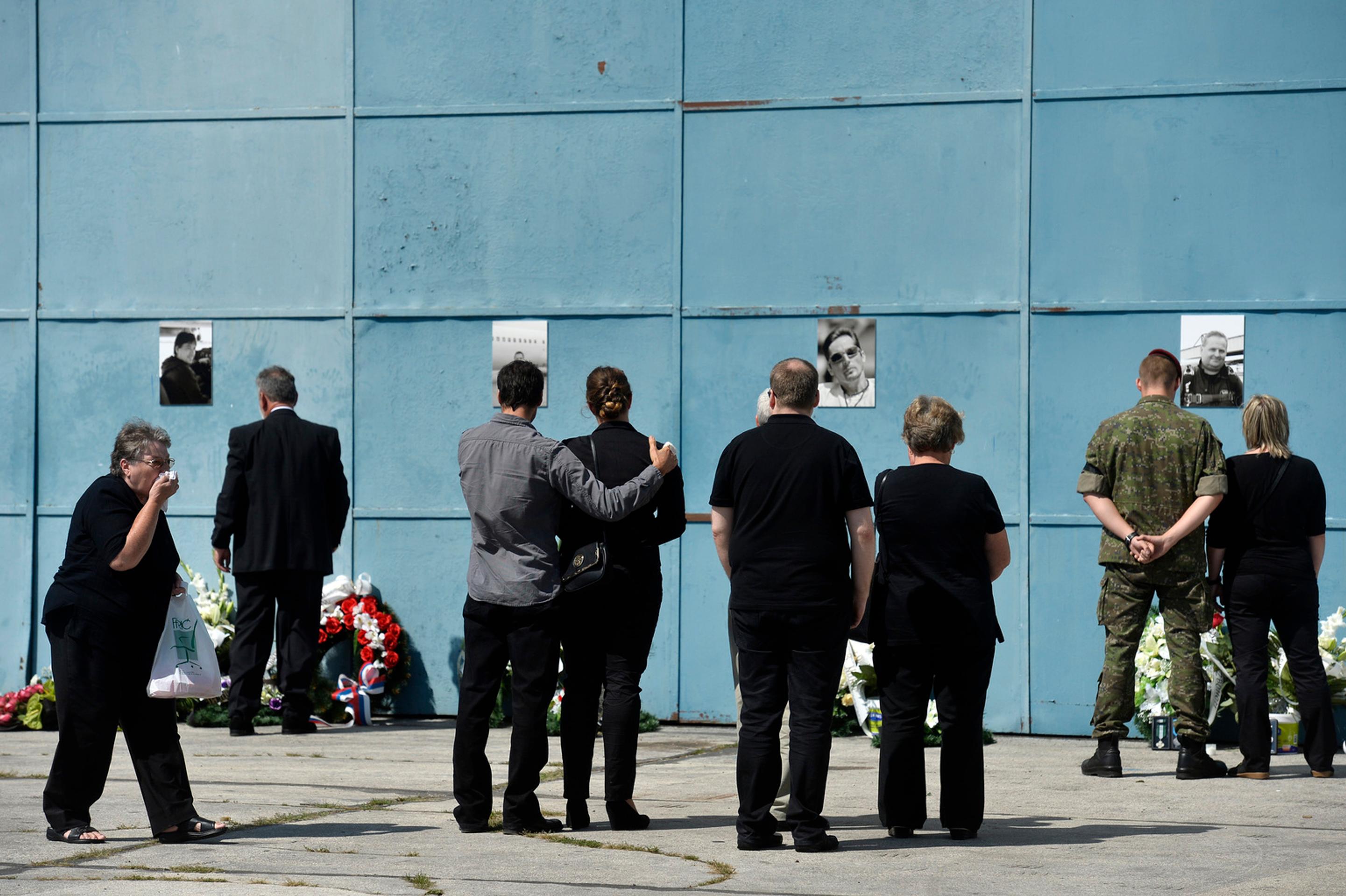 Pozostalí prinášajú kvety k fotografiám obetí leteckého nešťastia na bráne hangára na letisku v Slavnici