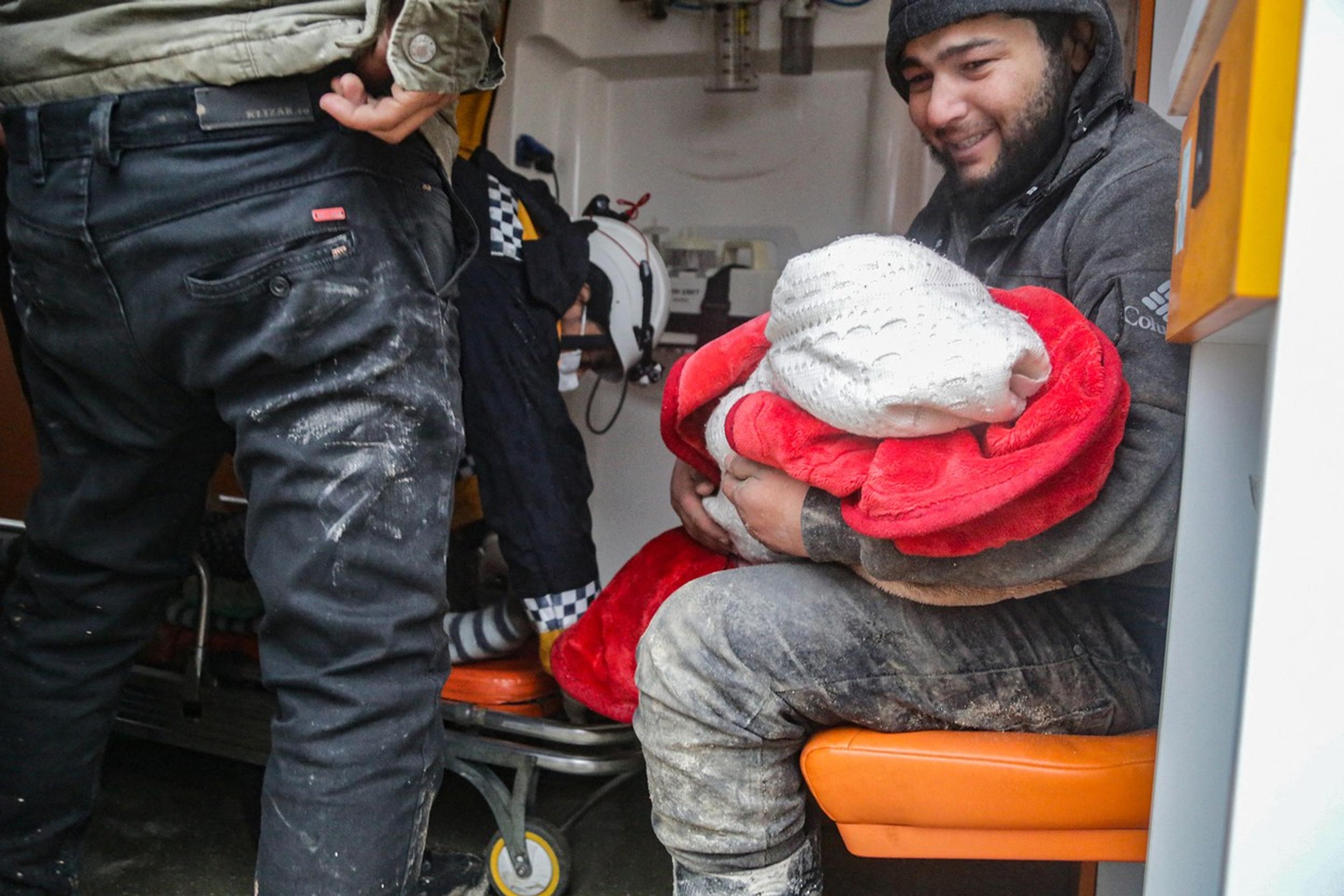 Muž drží v náručí dieťa po zemetrasení v sýrskom Aleppe.