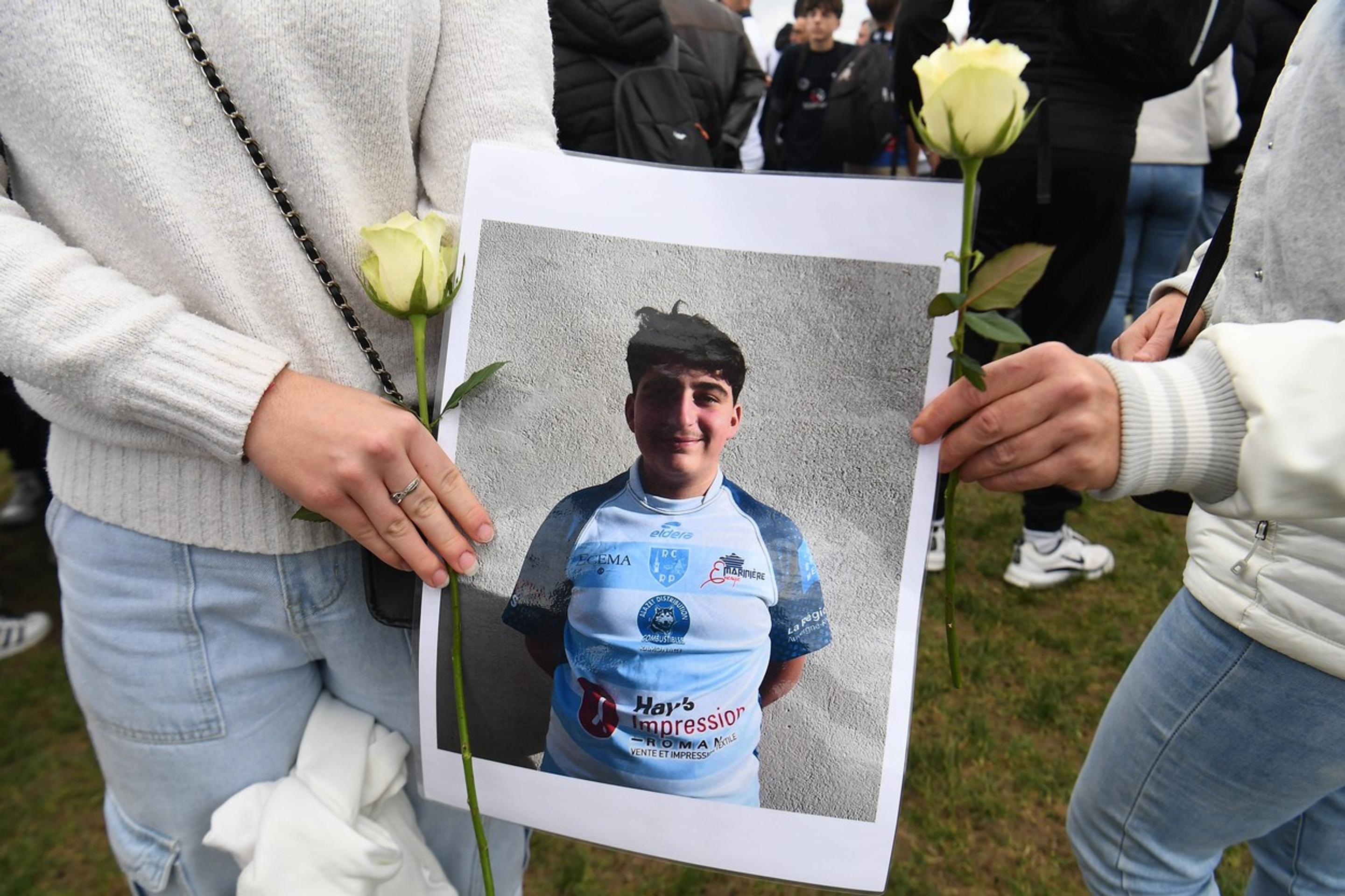 Smútiaci obyvatelia dediny s fotografiou zavraždeného Thomasa.