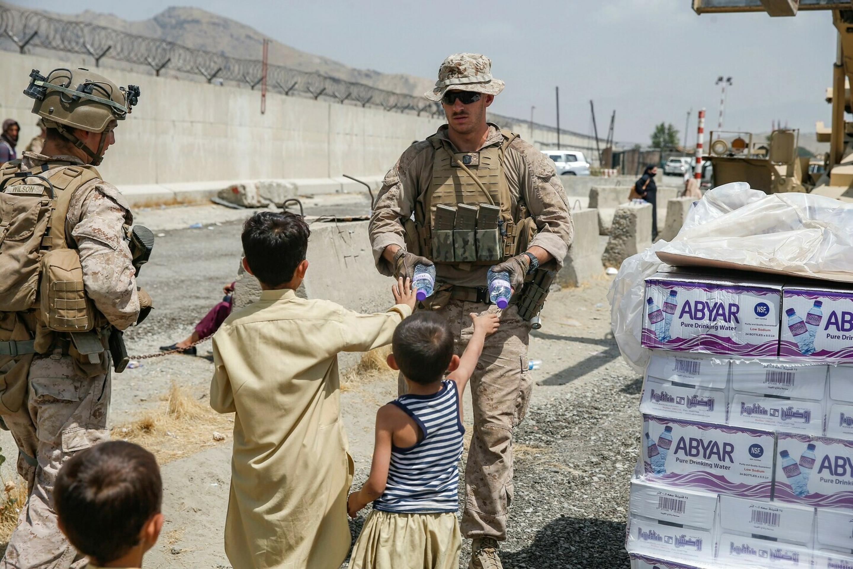 Americký vojak rozdáva afganským deťom balenú vodu.