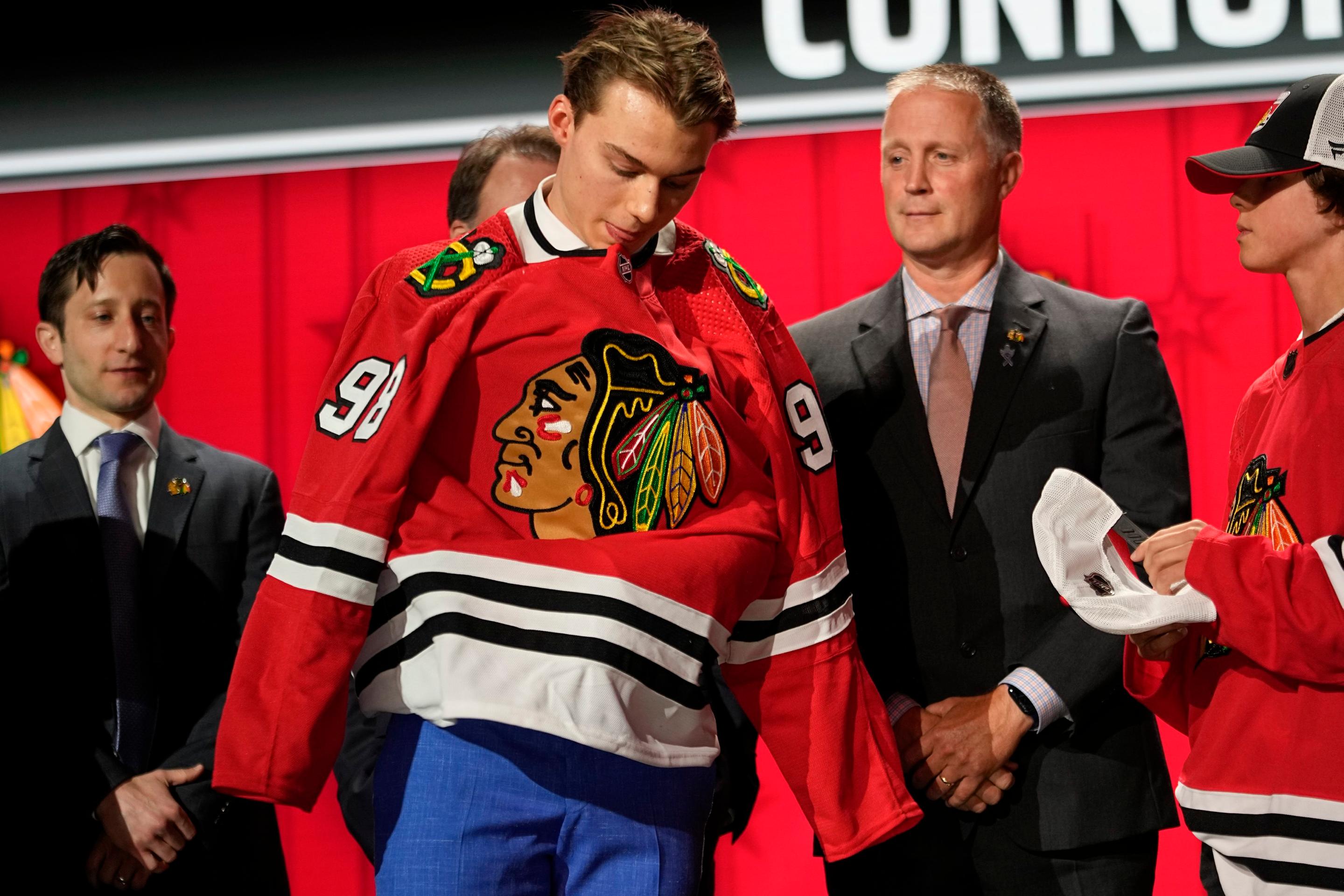 Connor Bedard si oblieka dres Chicaga na NHL drafte 2023.