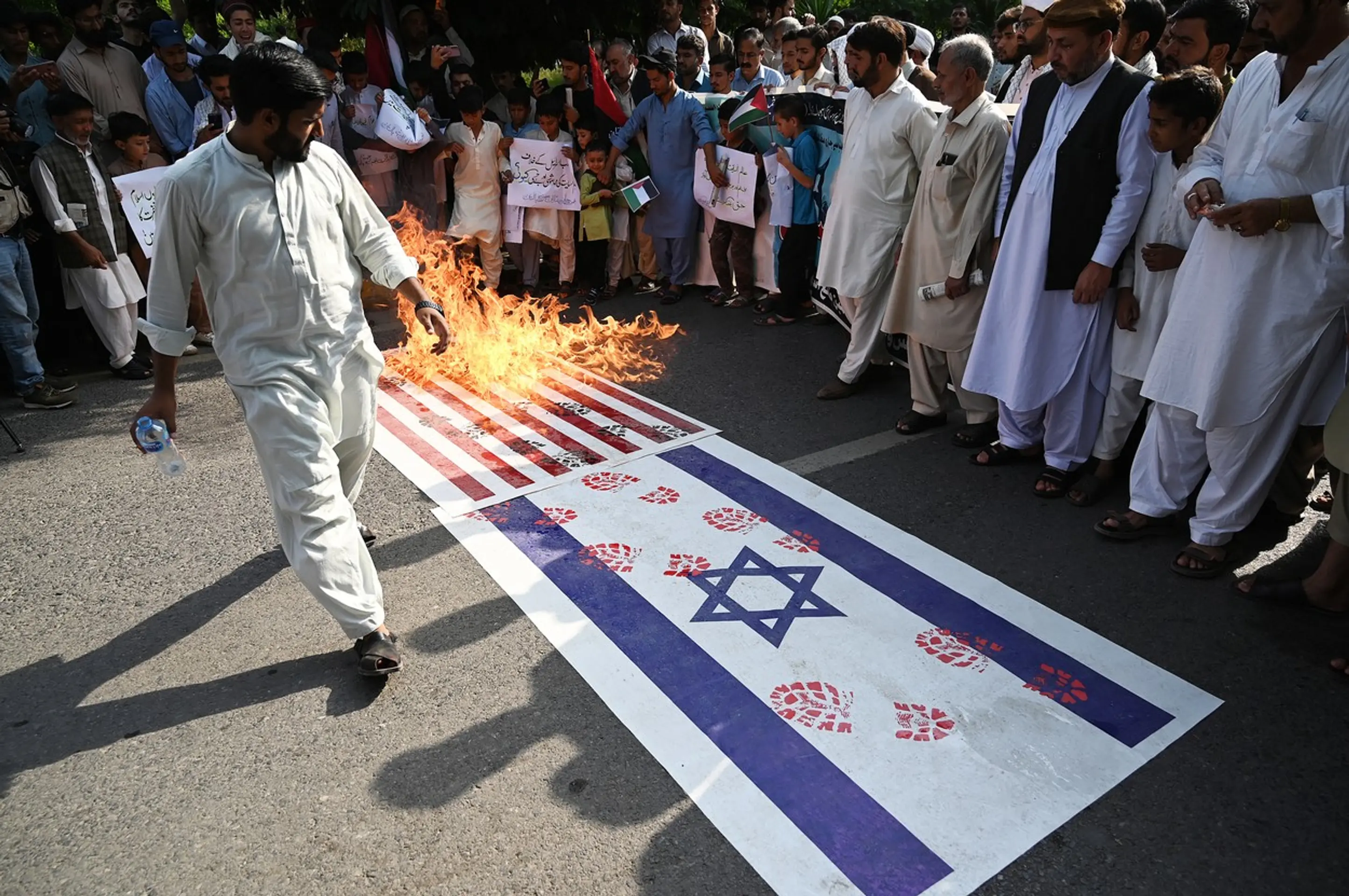 Pálenie izraelskej a americkej vlajky na protestnom zhromaždení v pakistanskom Islamabáde.