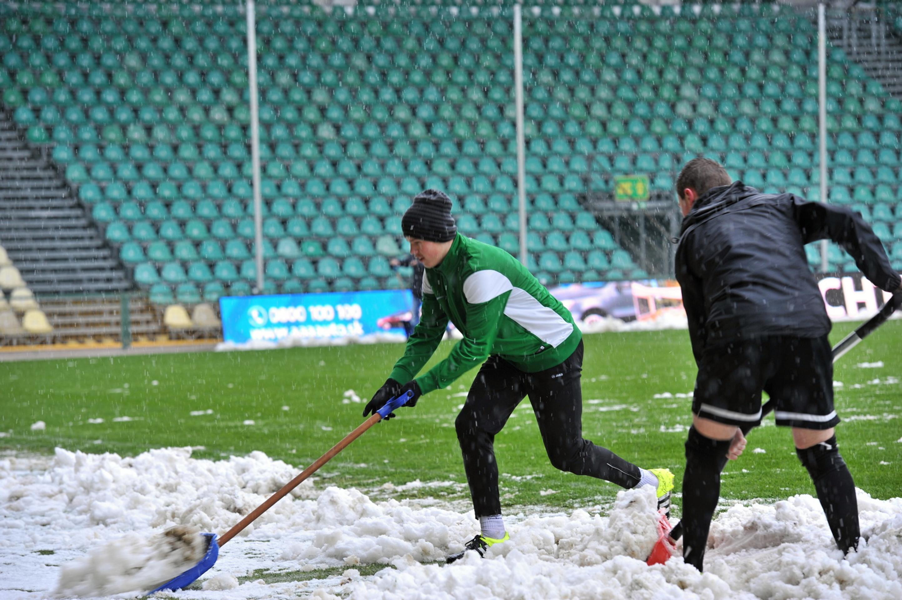 Zamestnanci odpratávajú sneh z hracej plochy na štadióne v Žiline pred zápasom s Trenčínom.