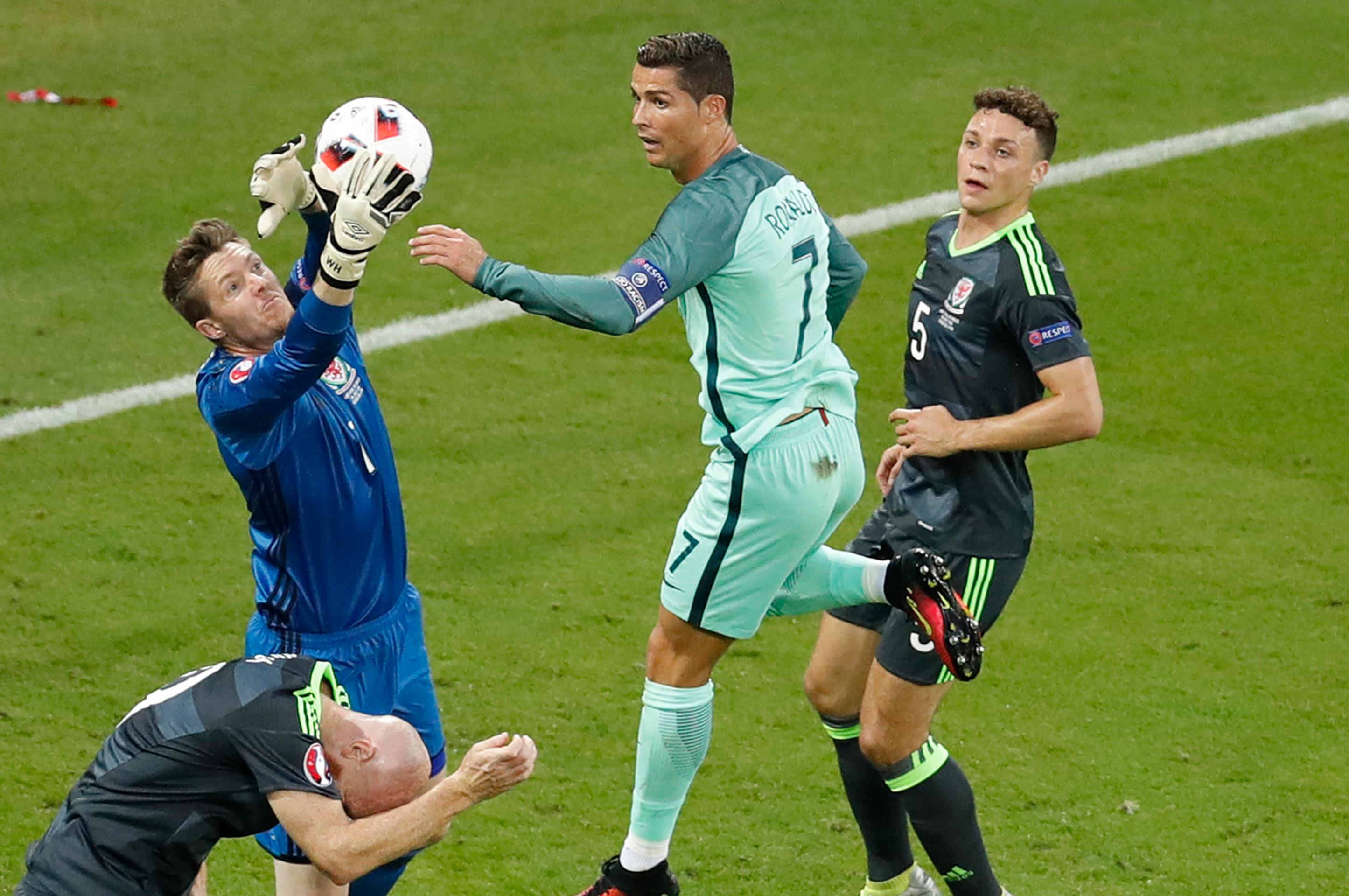 Waleský gólman Wayne Hennessey chytá loptu pred obávaným Cristianom Ronaldom z Portugalska v semifinále ME.