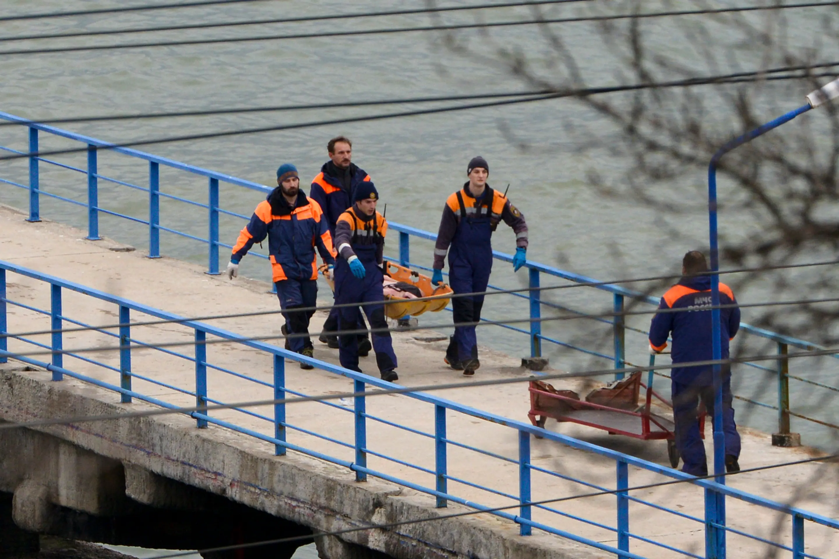 Ruskí záchranári nesú telo z vraku zrúteného lietadla typu Tu-154 na móle neďaleko Soči.