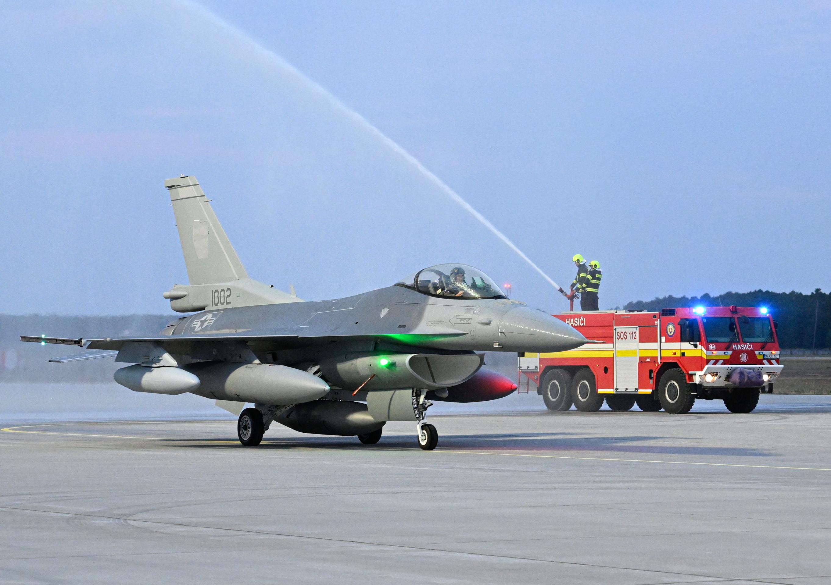 Jedna z dvoch stíhačiek F-16 symbolicky prechádza tzv. slávobránou z hasičských striekačiek v priestoroch Leteckej základne Malacky-Kuchyňa.