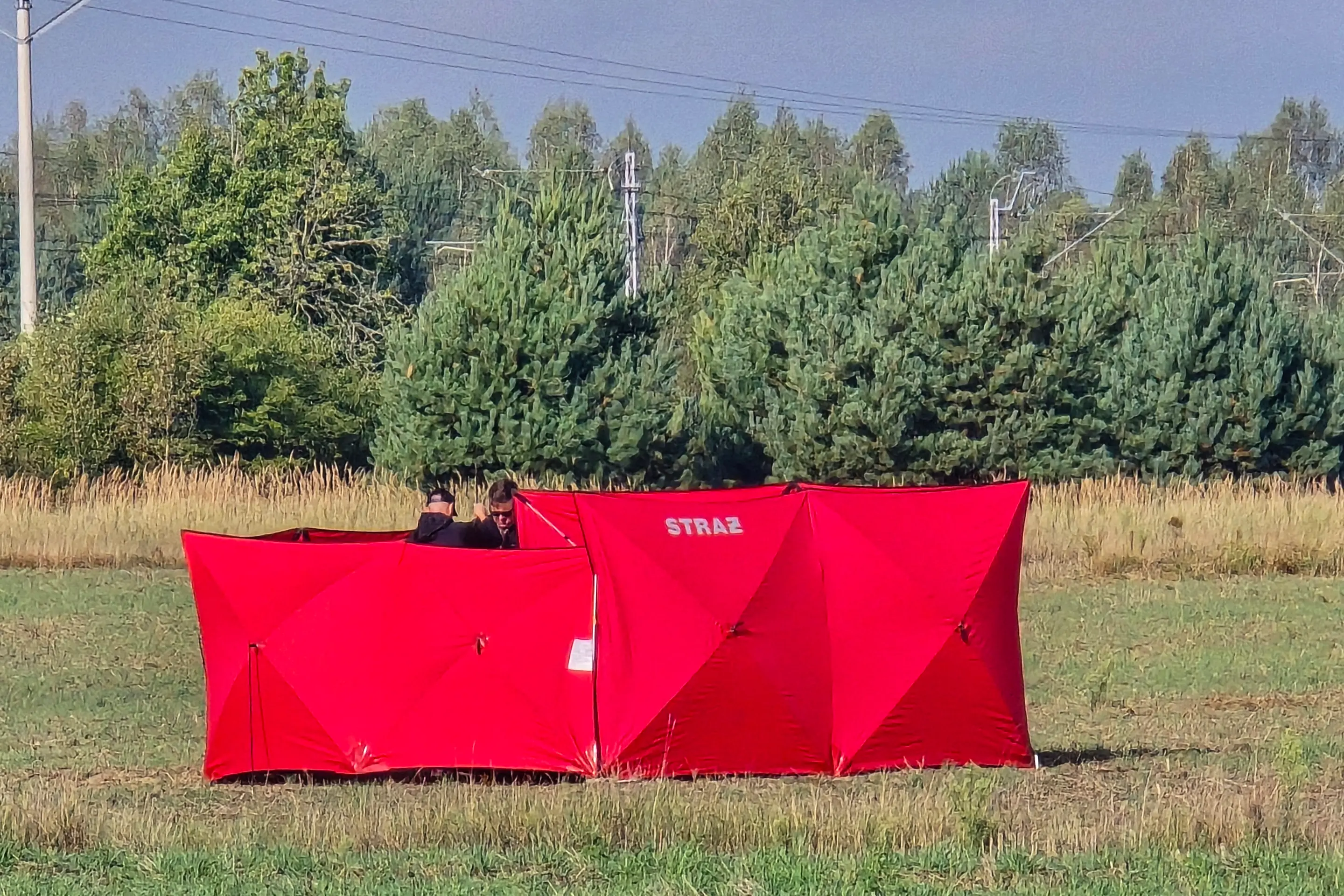 Hasiči zabezpečujú časť úlomkov jedného z dronov, ktoré v noci na stredu narušili vzdušný priestor Poľska, v poľskej dedine Czosnówka.