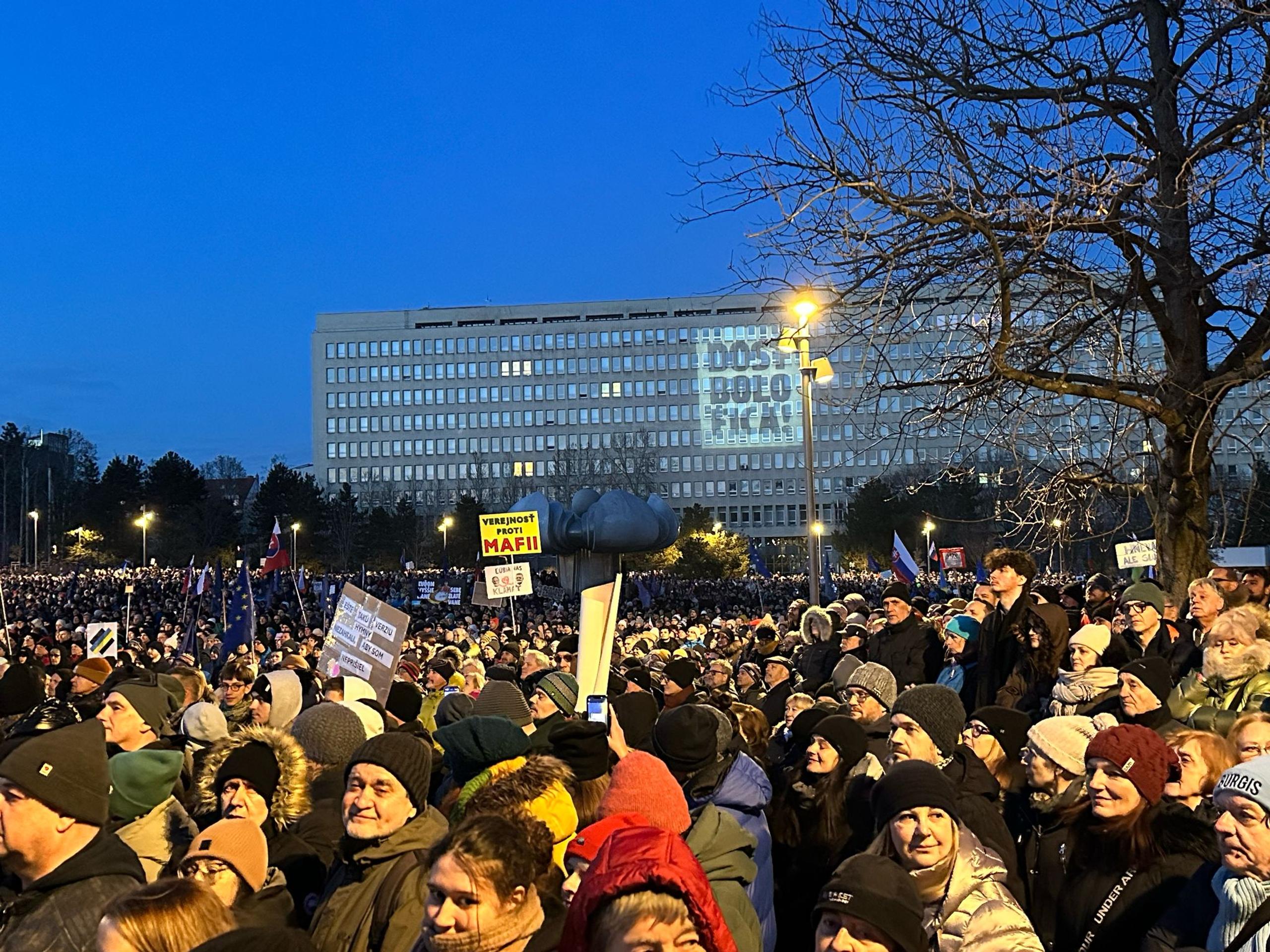 Protestujúci s nápisom projektovaným na budove