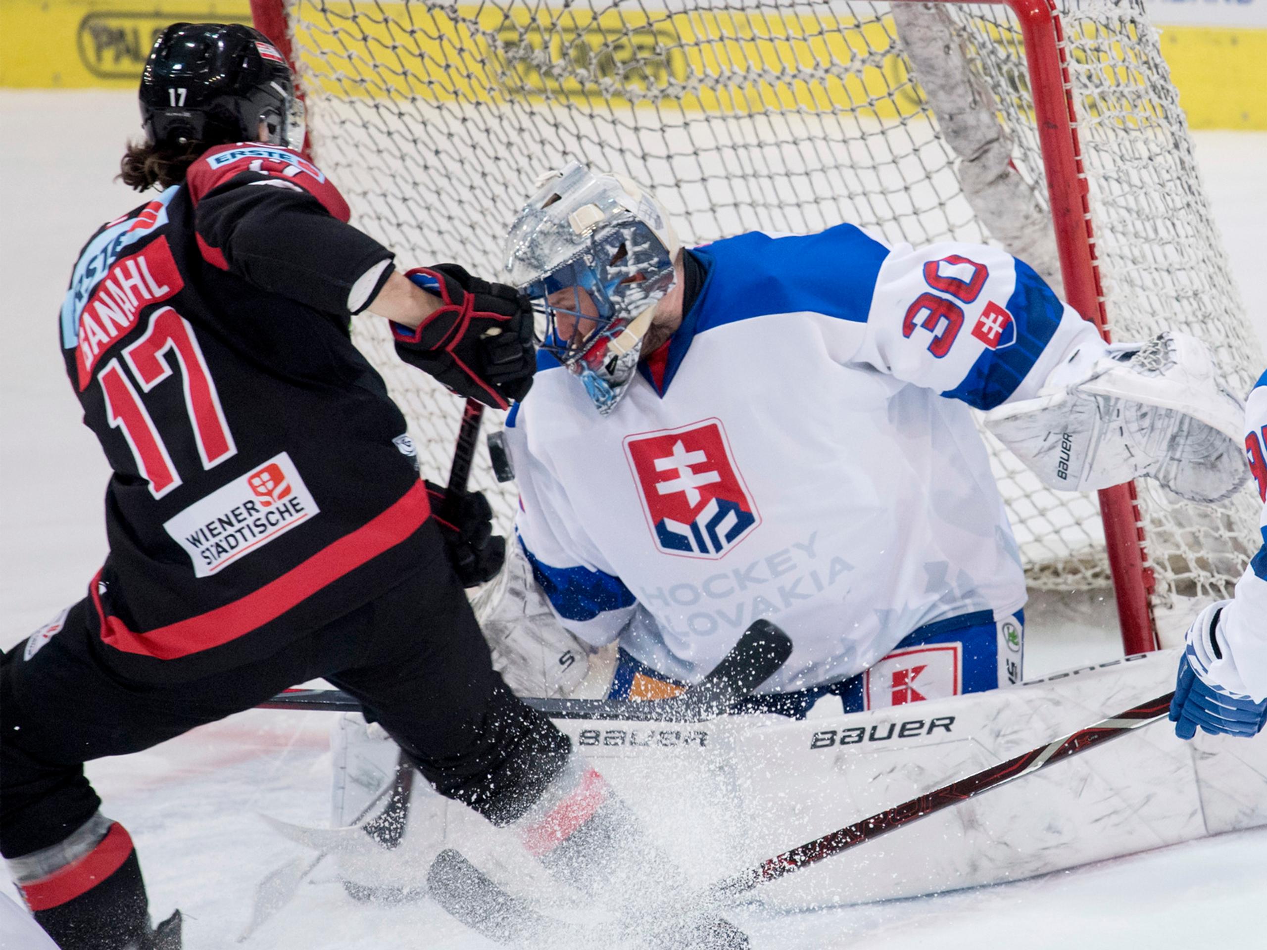 Sprava Denis Godla chytá puk pred Rakúšanom Manuelom Ganahlom v zápase Euro Hockey Challenge.