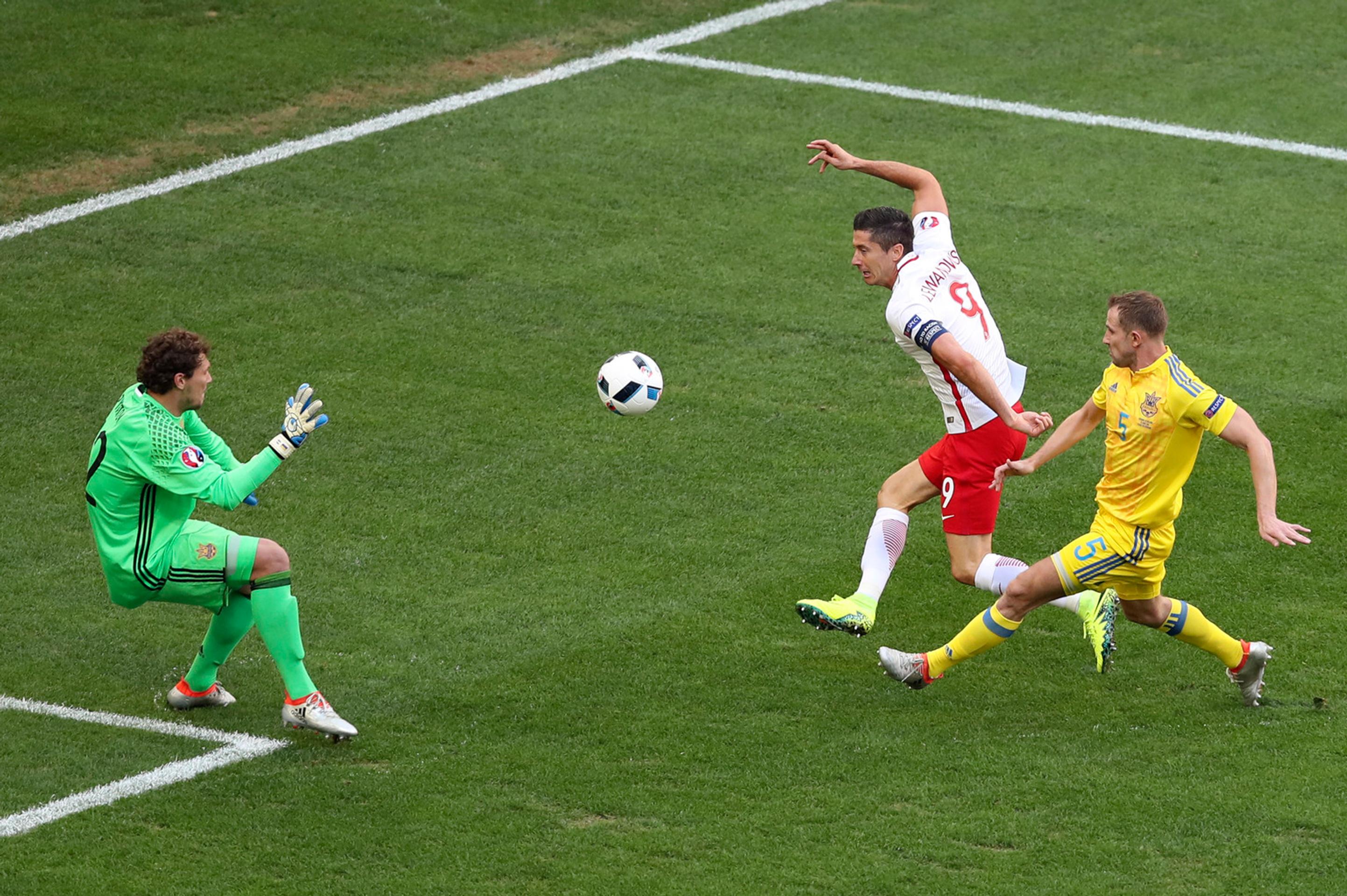 Kanonier Poľska Robert Lewandowski (druhý sprava) v šanci pred brankárom Ukrajiny Andrijom Piatovom (vľavo)