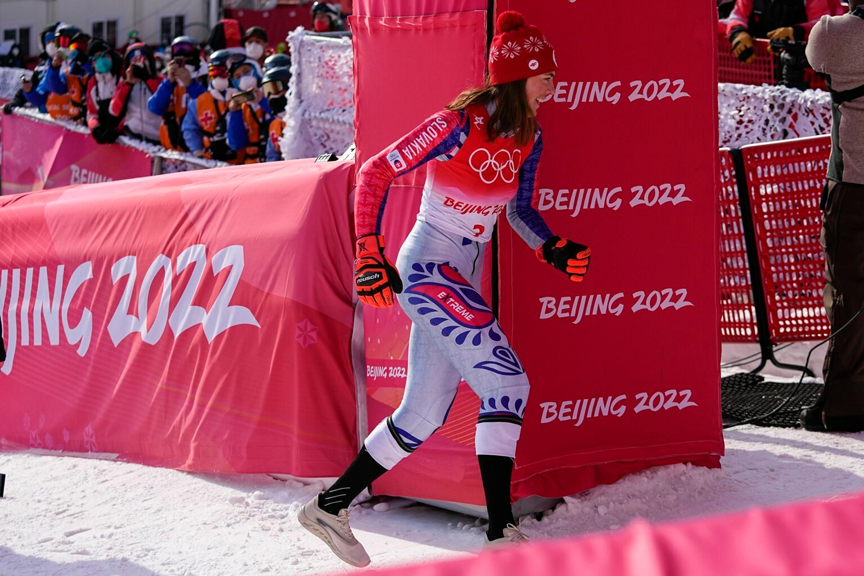 Lyžiarka Petra Vlhová uteká za svojim tímom oslavovať zlato v slalome na ZOH 2022.
