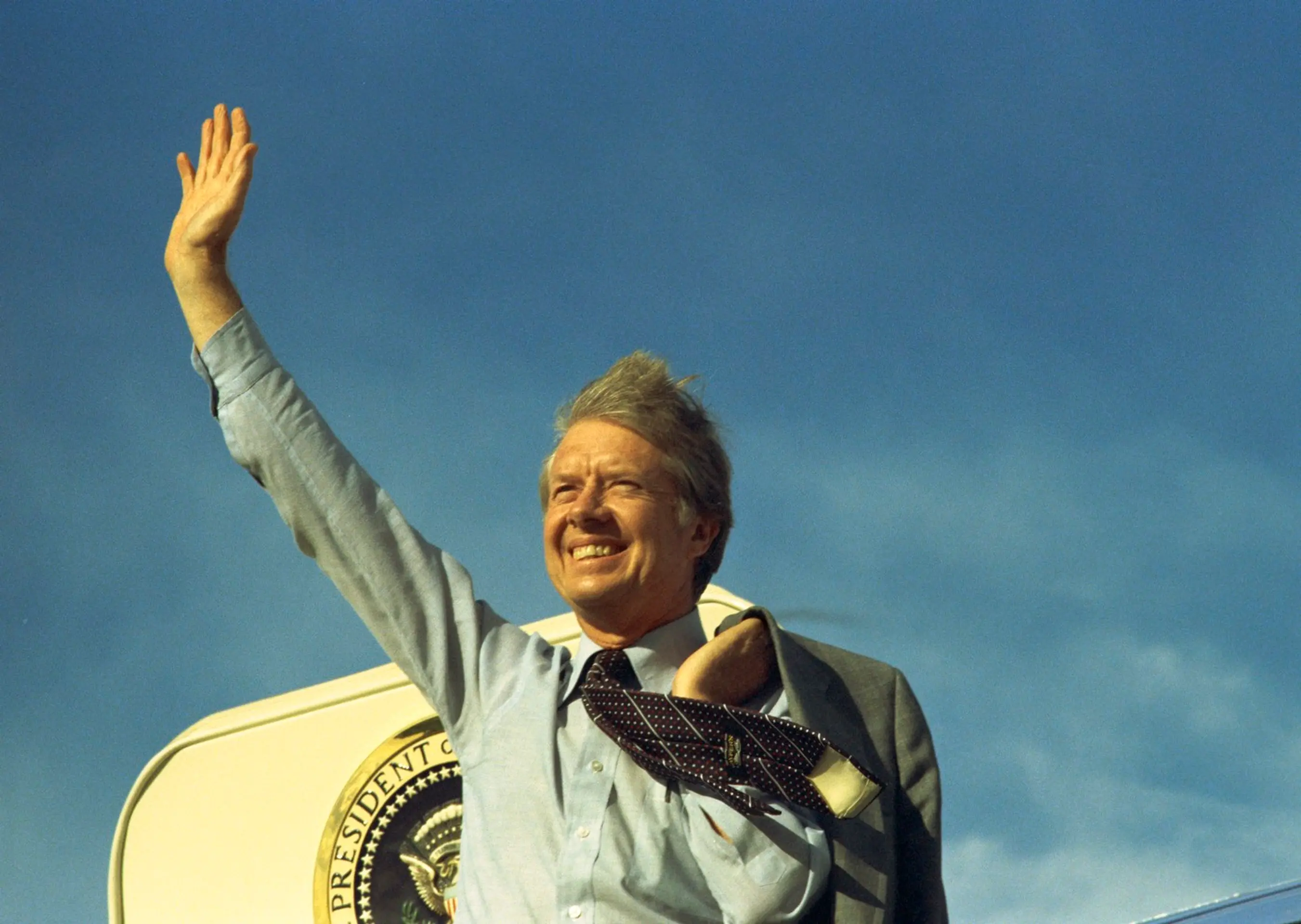 Americký prezident Jimmy Carter mával na schodoch Air Force One pred odletom do Los Angeles, aby vystúpil na zjazde United Auto Workers 17. mája 1977.