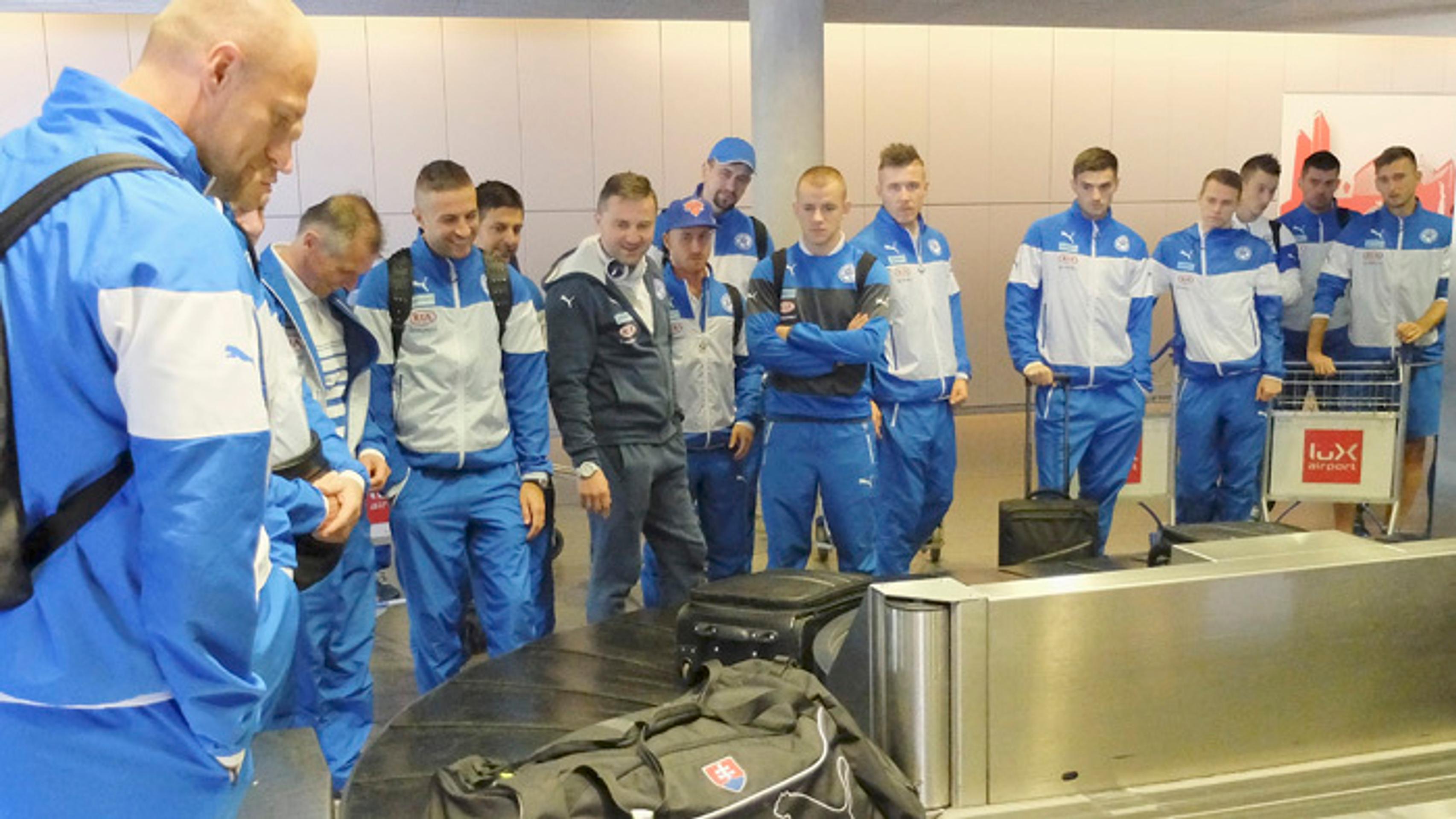 Futbaloví reprezentanti čakajú na batožinu po prílete do Luxemburgu. 