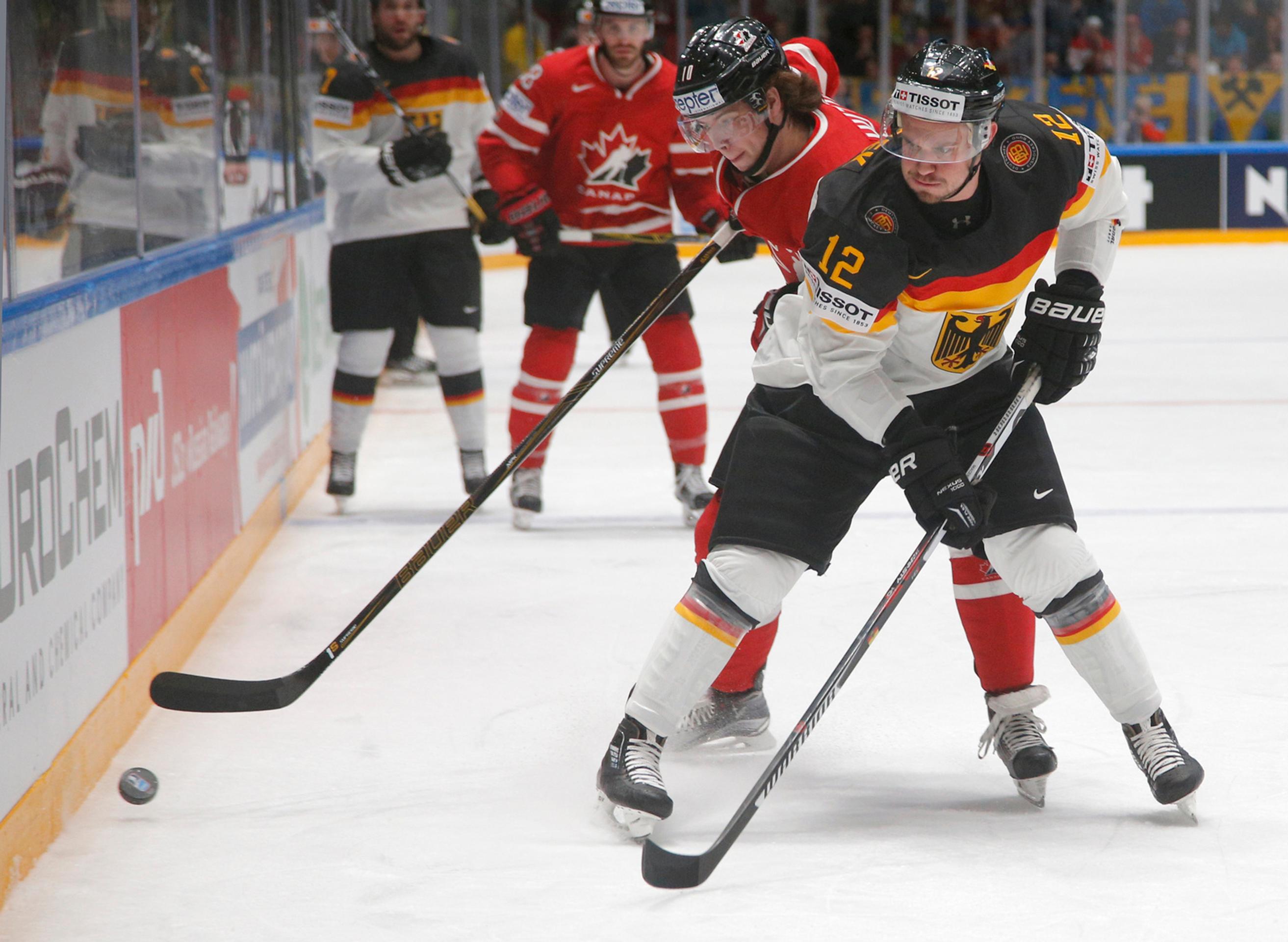 Hráč Kanady Ben Hutton (vľavo) a hráč Nemecka Patrick Hager (vpravo) v súboji o puk v zápase B-skupiny MS v Rusku.