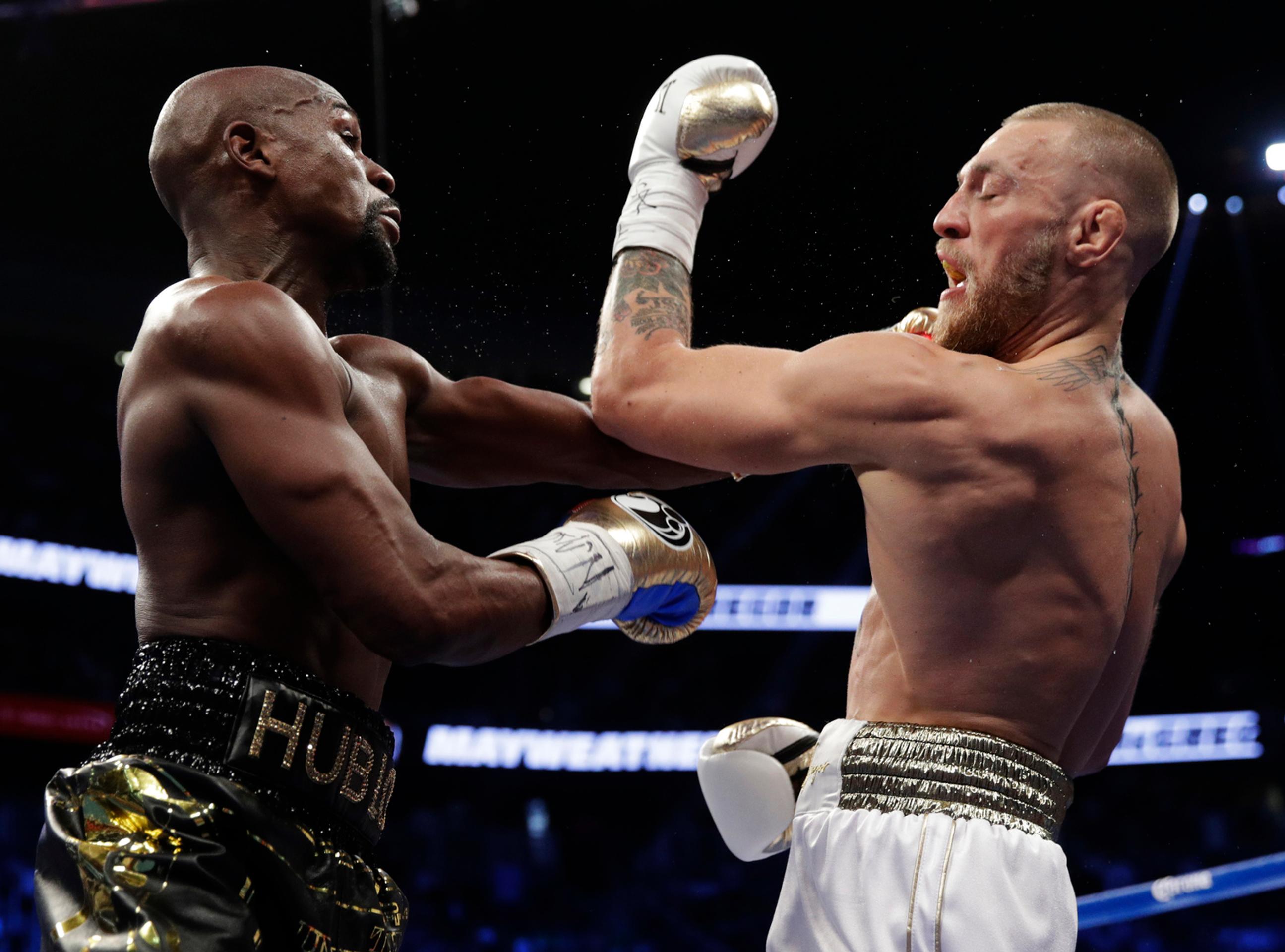 McGregor (vpravo) inkasuje úder od Mayweathera.