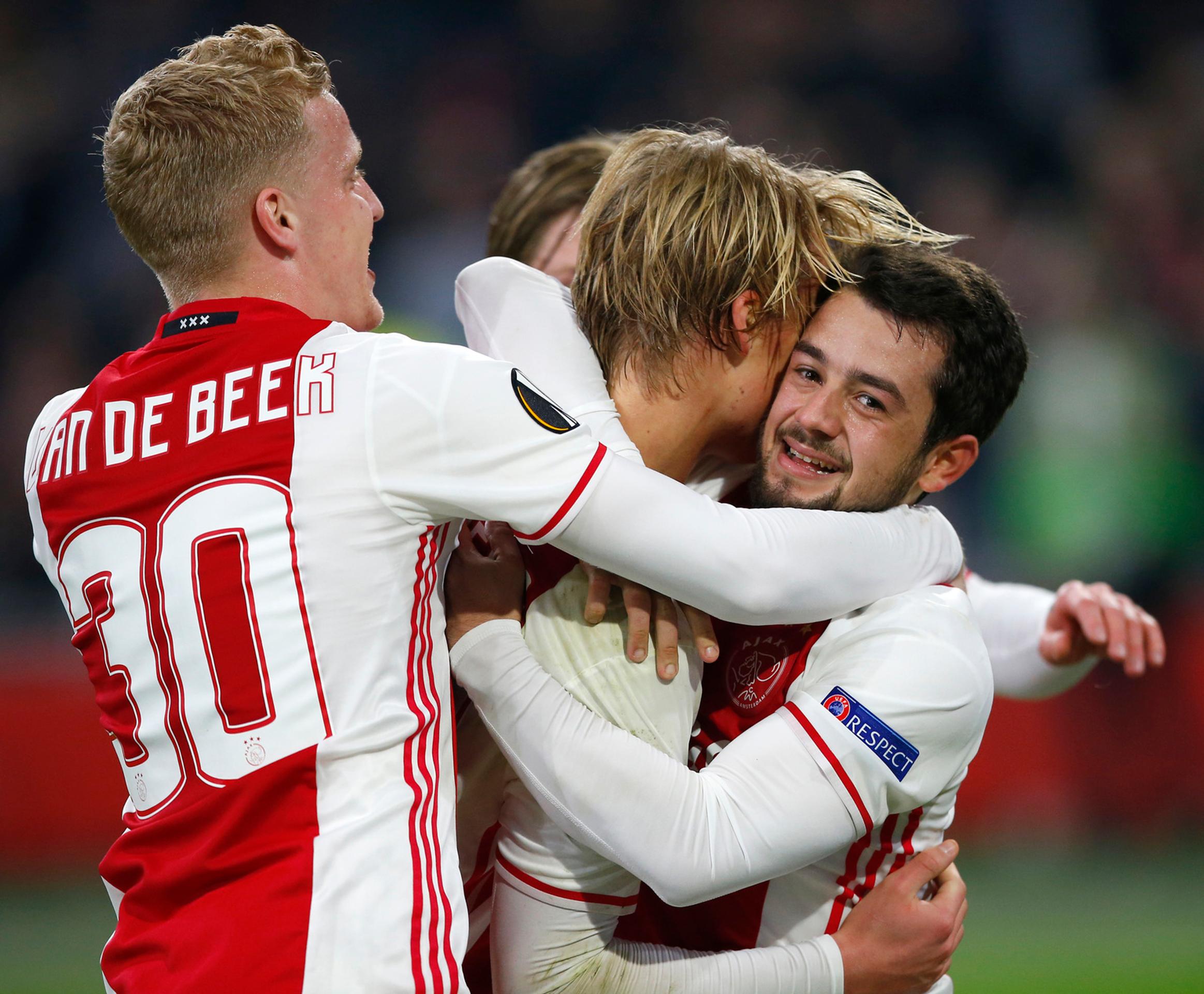 Donny van Beek (vľavo) a Amin Younes (vpravo) objímajú spoluhráča z Ajaxu Kaspara Dolberga po góle v odvete osemfinále EL proti 