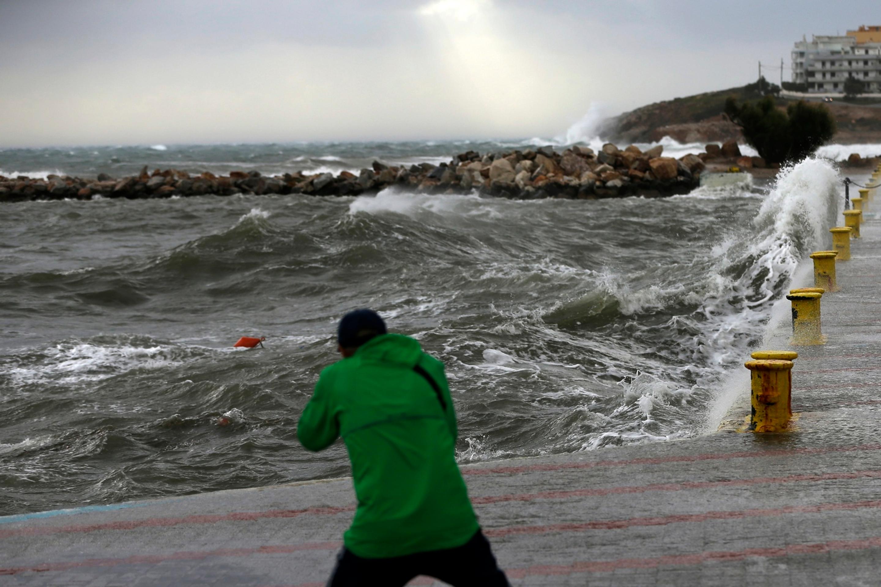 Muž si fotí obrovské vlny počas nepriaznivého počasia v prístavnom meste Rafina.