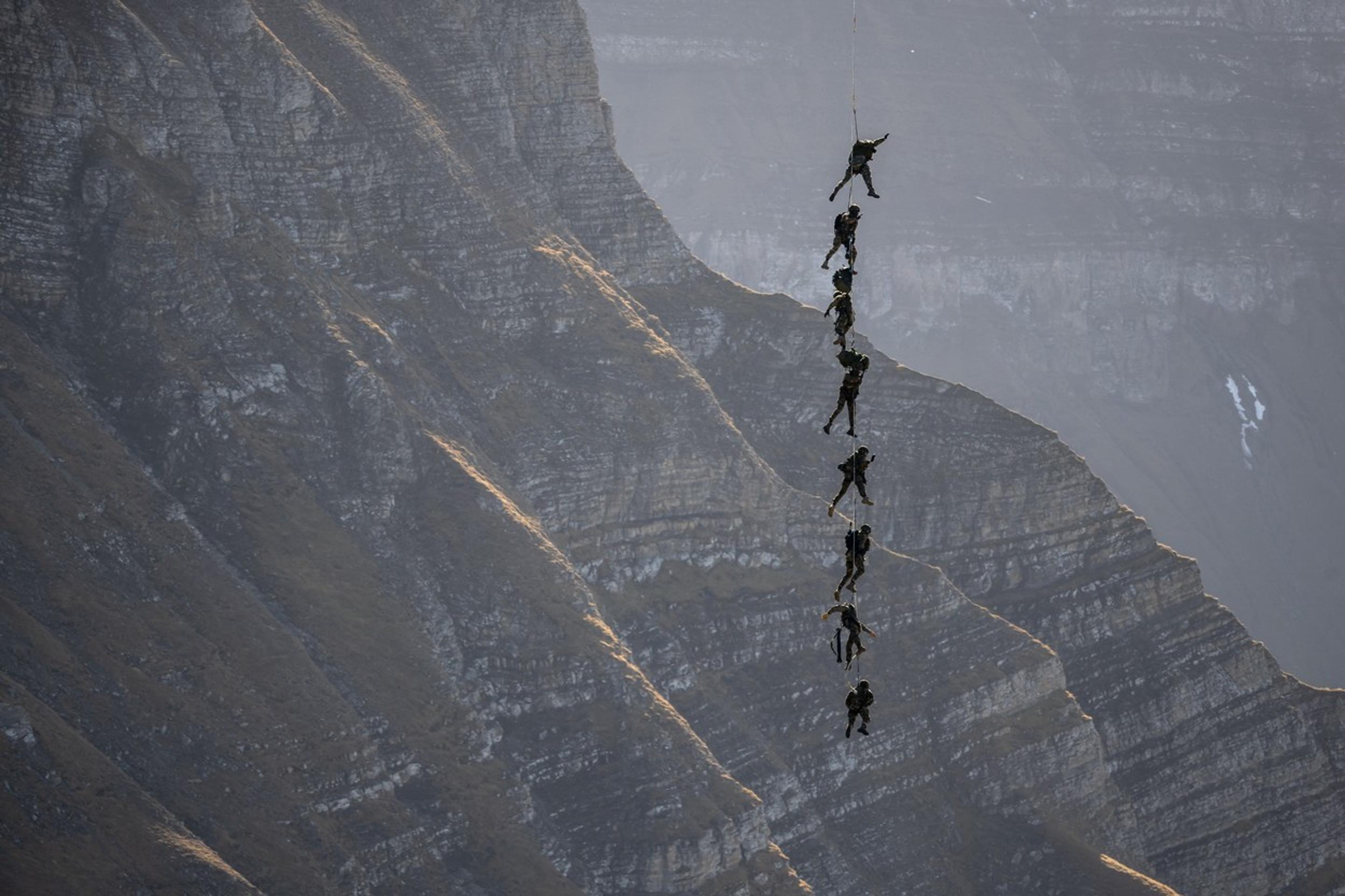Príslušníci špeciálnych jednotiek švajčiarskej armády visia na lane počas leteckej šou nad lyžiarskym strediskom Axalp.