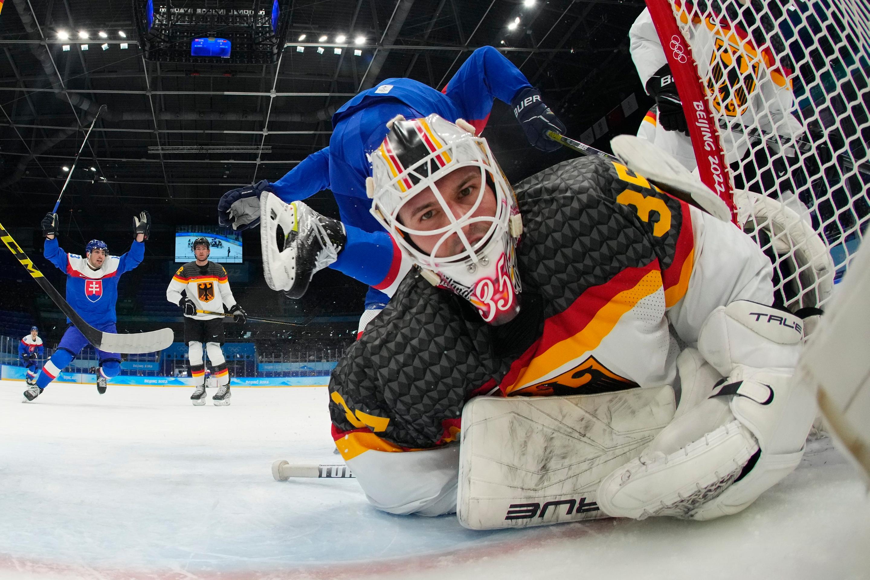 Nemecký brankár Mathias Niederberger v kolízii s Tomášom Jurčom v kvalifikačnom stretnutí ZOH 2022.