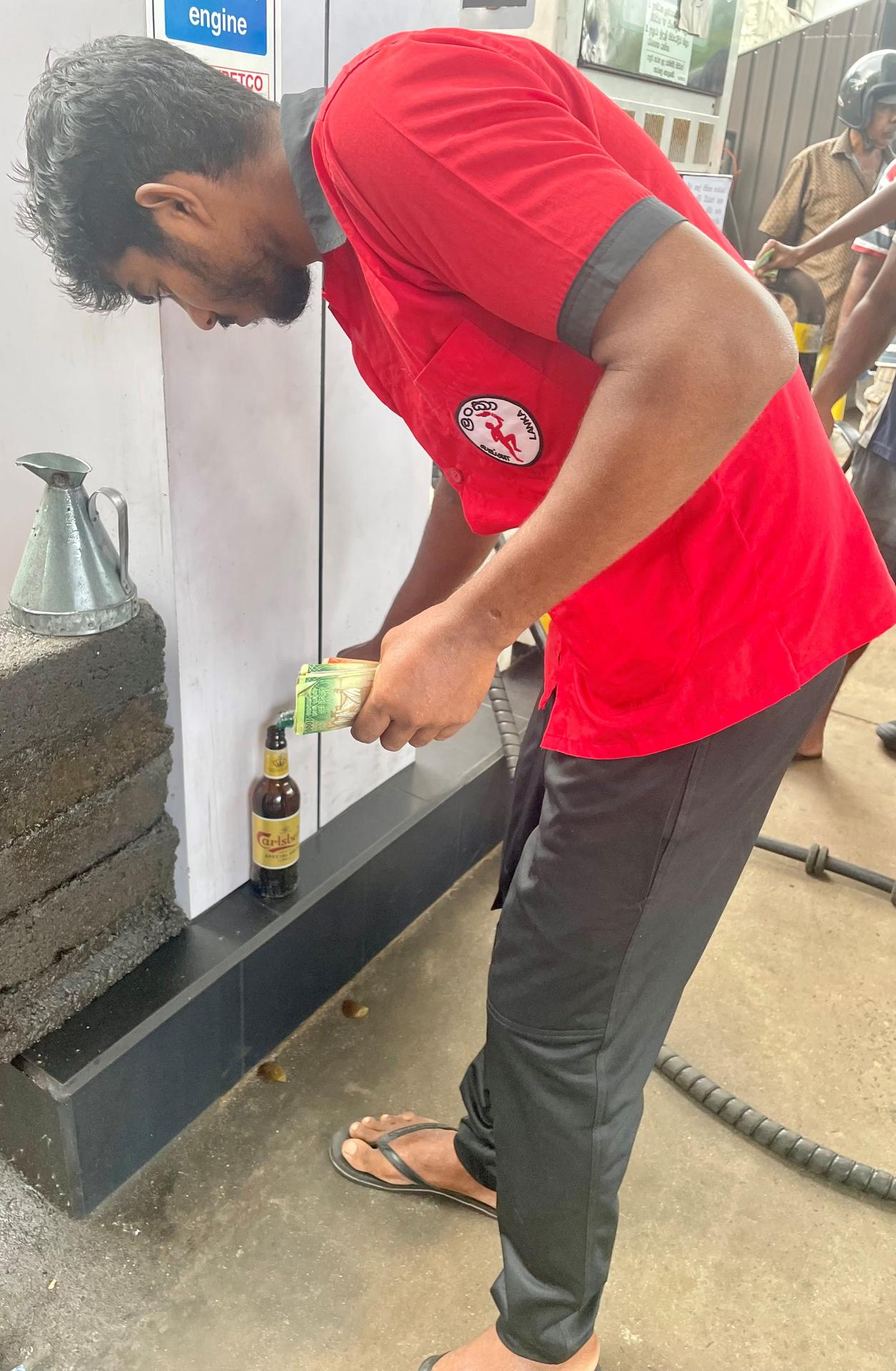 Muž tankujúci benzín do pivovej fľaše