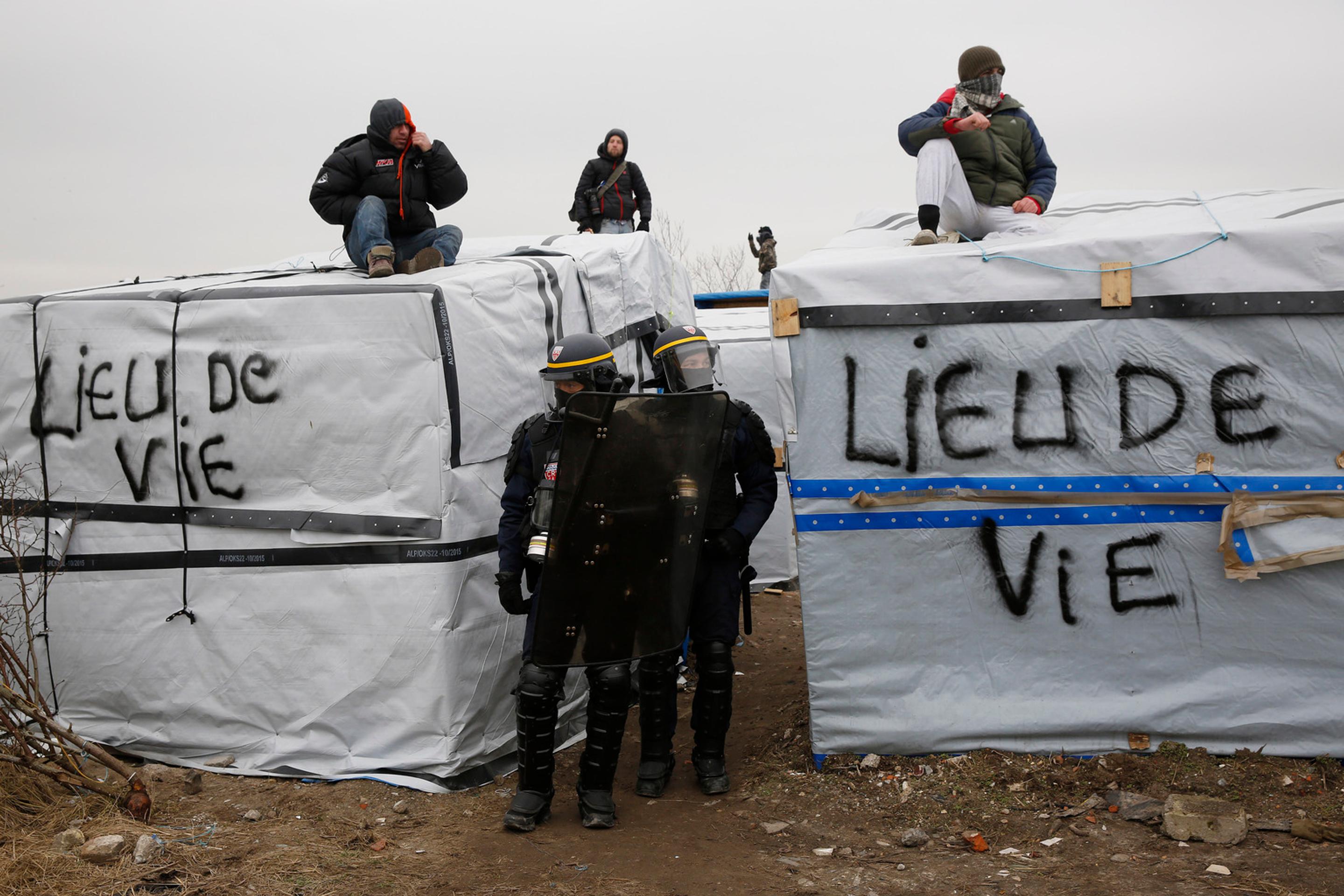 Migranti v tábore pri Calais protestujú na strechách búd.