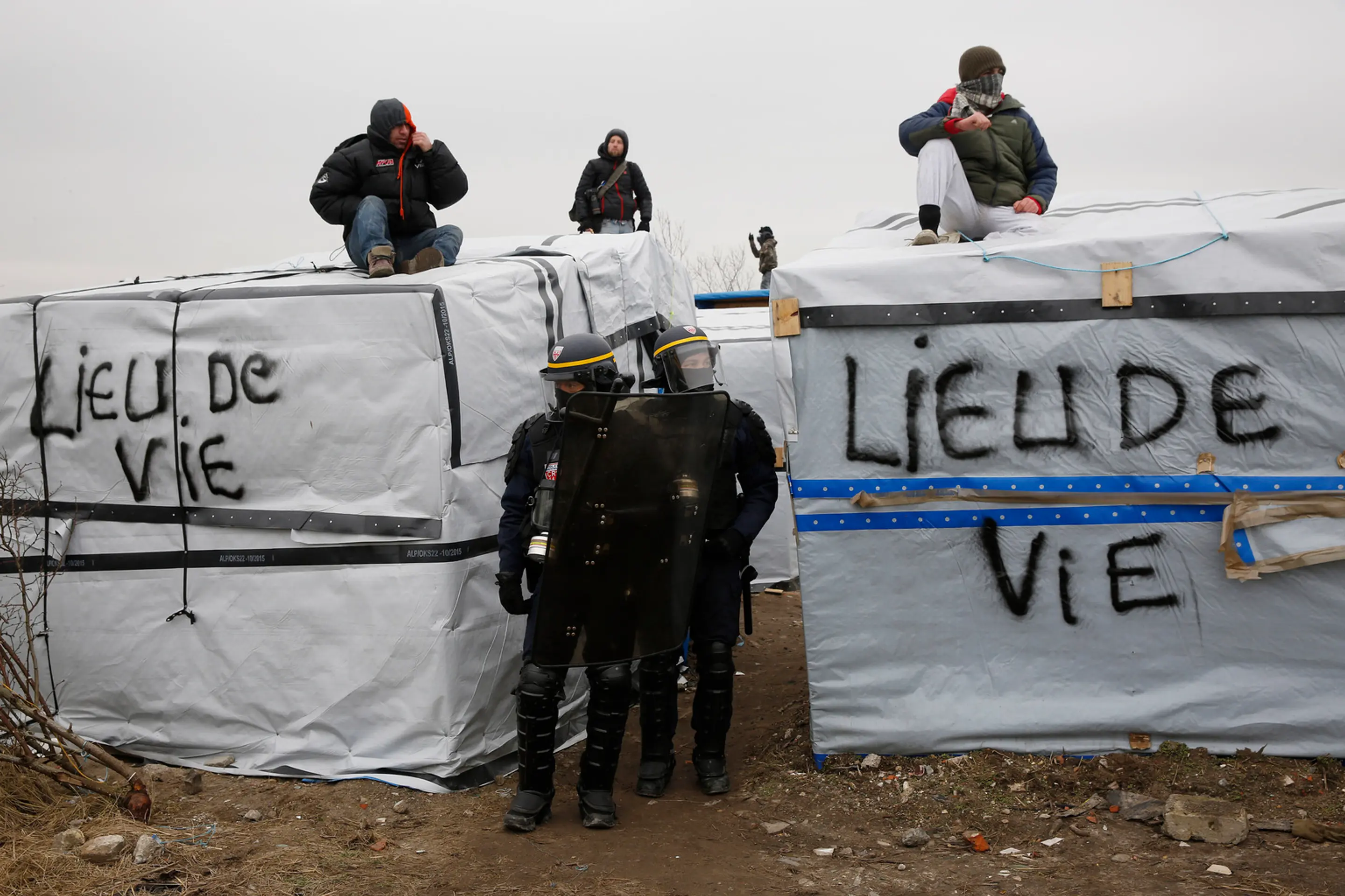 Migranti v tábore pri Calais protestujú na strechách búd.