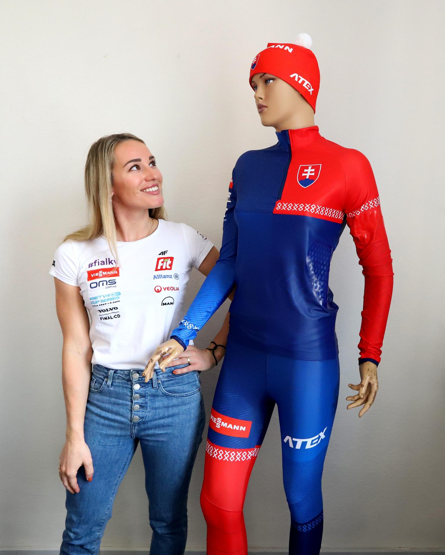 Paulína Bátovská Fialková stojí pri novej reprezentačnej kombinéze počas tlačovej konferencie Slovenského zväzu biatlonu.