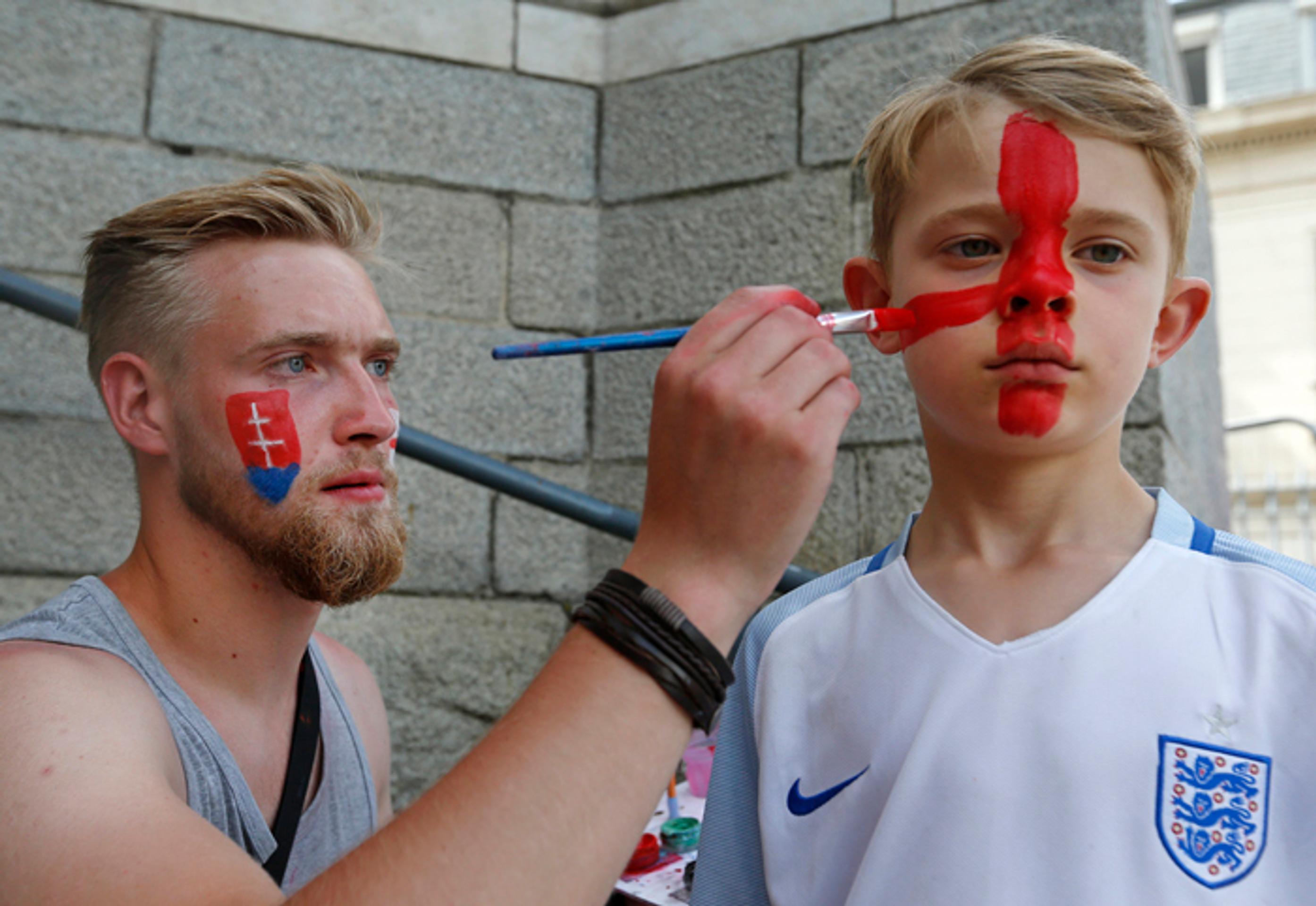 Muž na ulici maľuje malého fanúšika Anglicka.